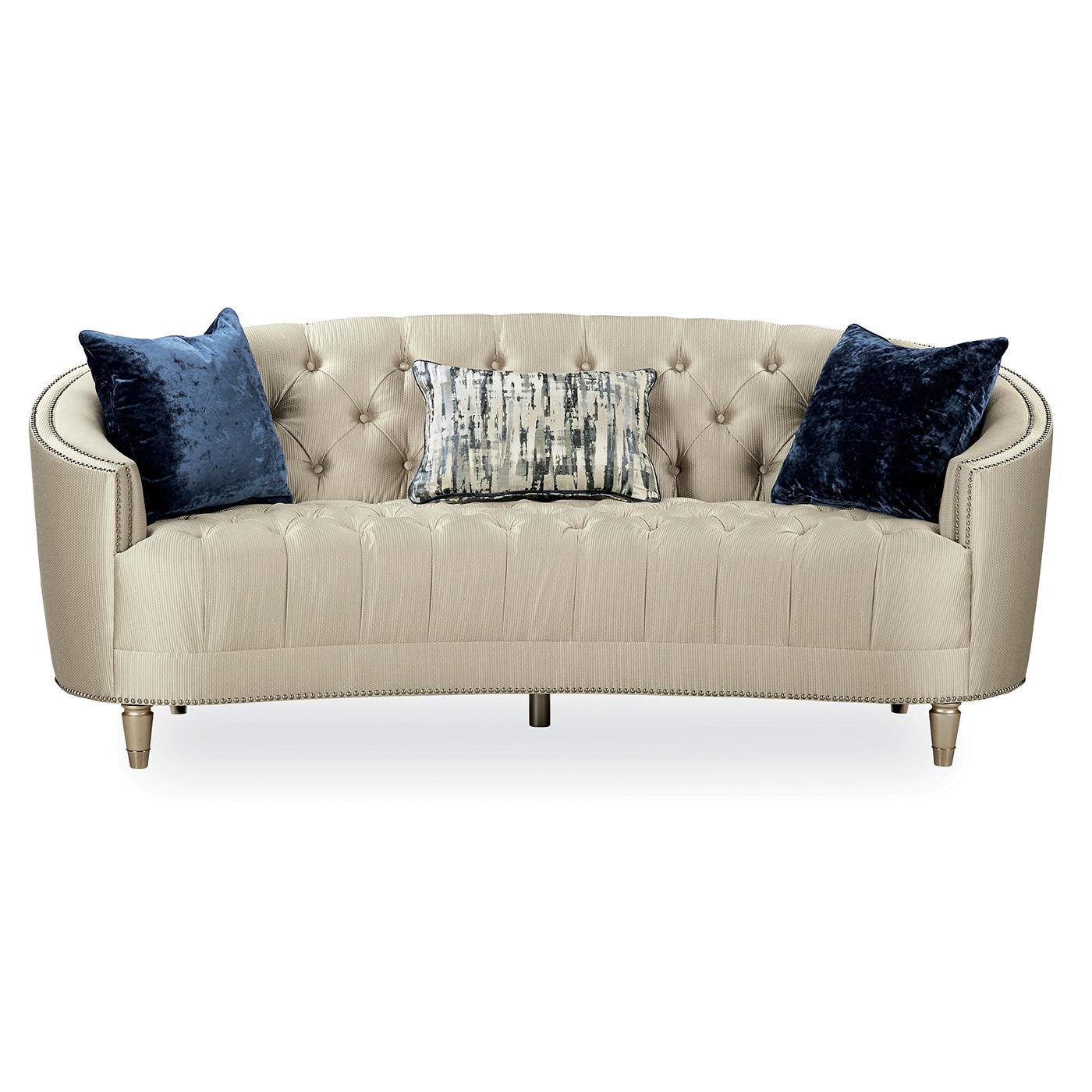 A transitional tufted curved back bench seat sofa. Curvaceous and shapely, with traditional elements like button-tufting and decorative nailhead trim, this bench seat sofa also conveys a modern sensibility, with metallic accents on the pillows. An