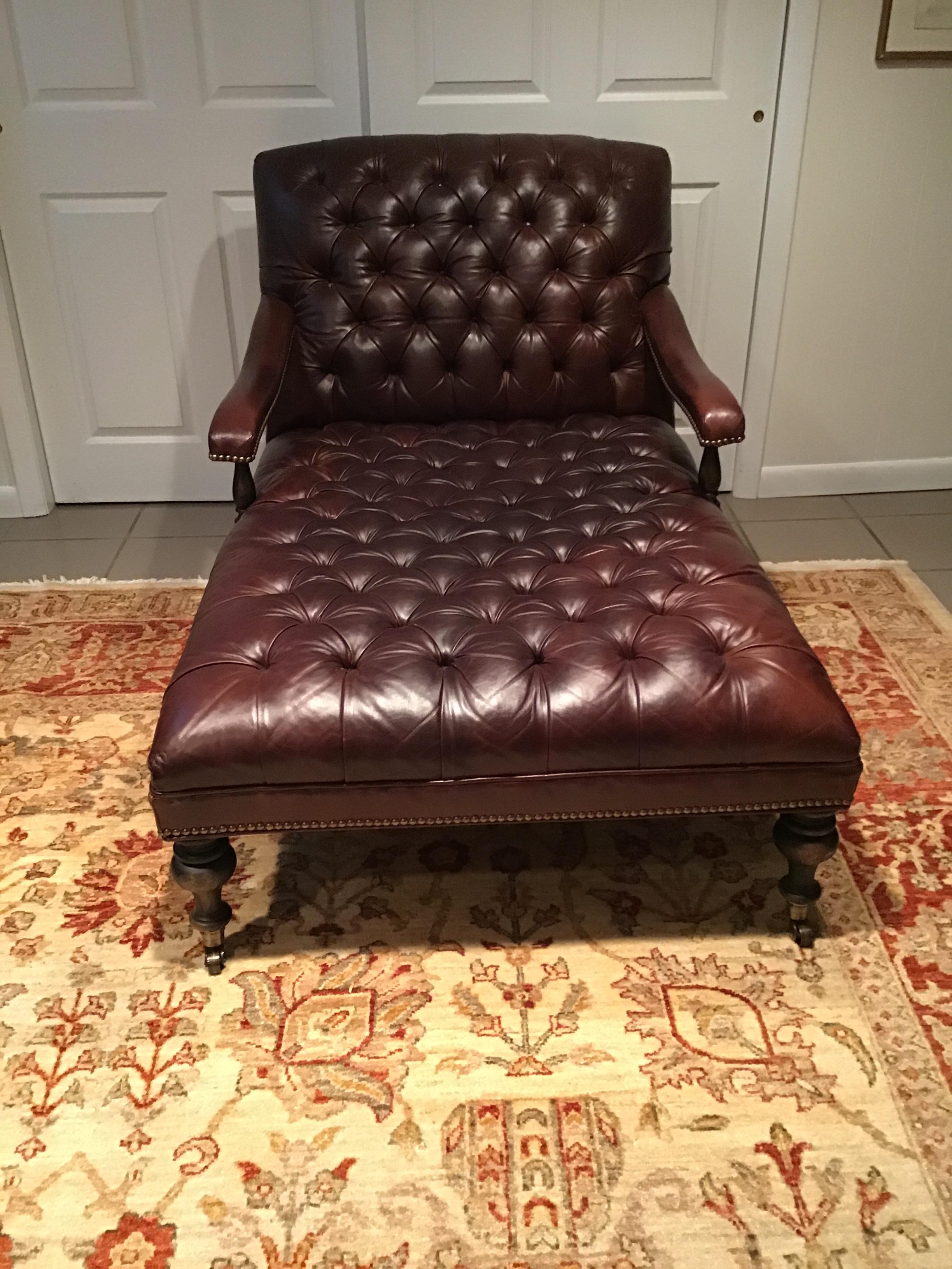 Tufted leather chaise lounge on wood legs with casters.