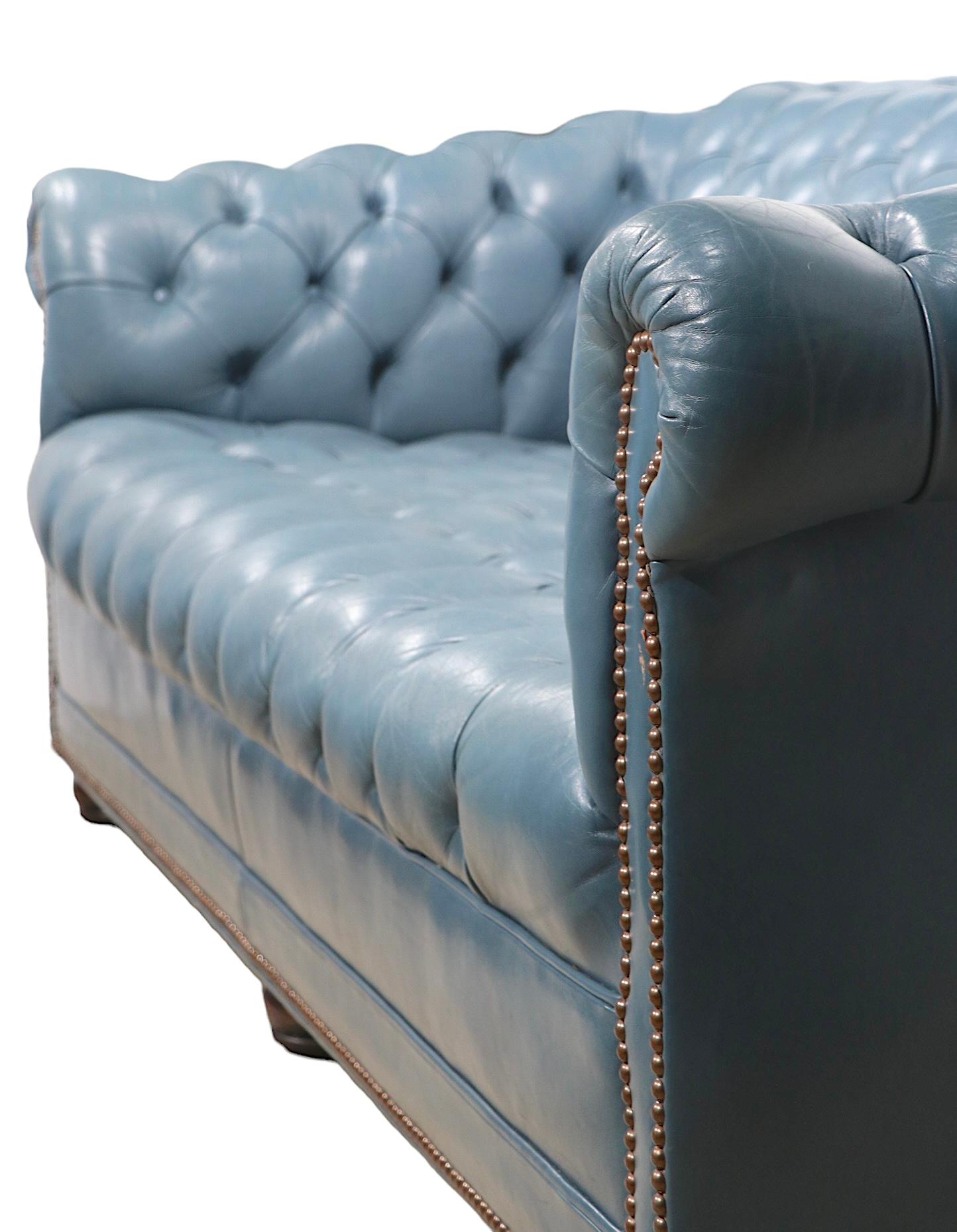 Chic, voguish and sophisticated  Chesterfield sofa  in intriguing French Blue tufted leather. with solid wood bun feet.  The sofa is in very good, original, clean and ready to use condition, showing only light cosmetic wear, normal and consistent
