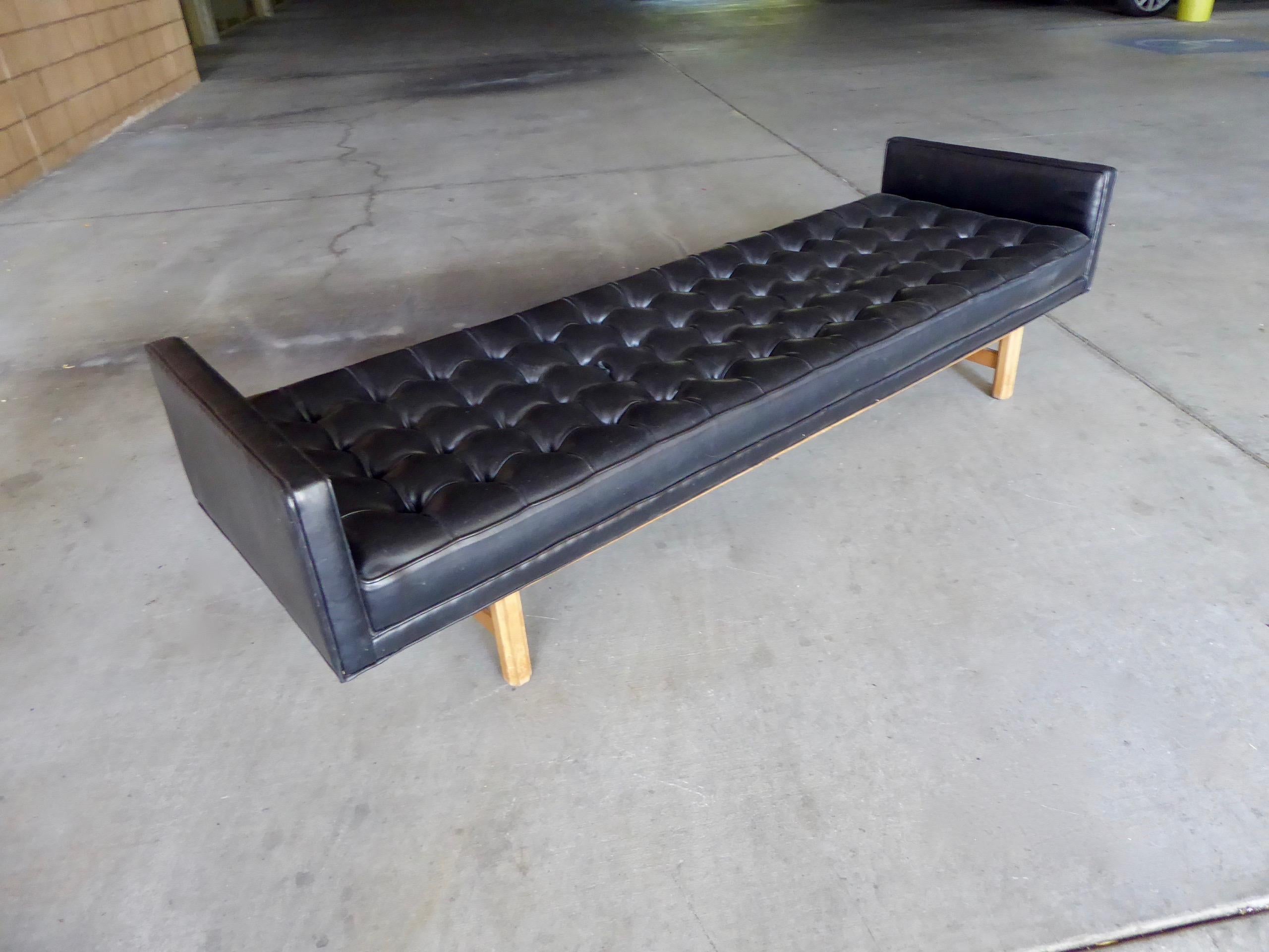 A long and sexy tufted black leather bench or daybed attributed to The Dunbar Furniture Co., circa 1960s. The base is made of mahogany and is discreetly setback from the edges. The leather is original and is in excellent vintage condition. This