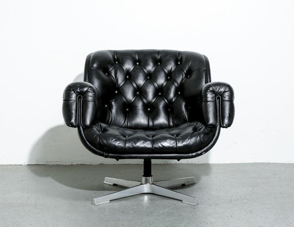 Lounge chair upholstered in a Chesterfield-style tufted black leather over a cast aluminum modernist base. In the style of Ward Bennett. Measure: 13.5