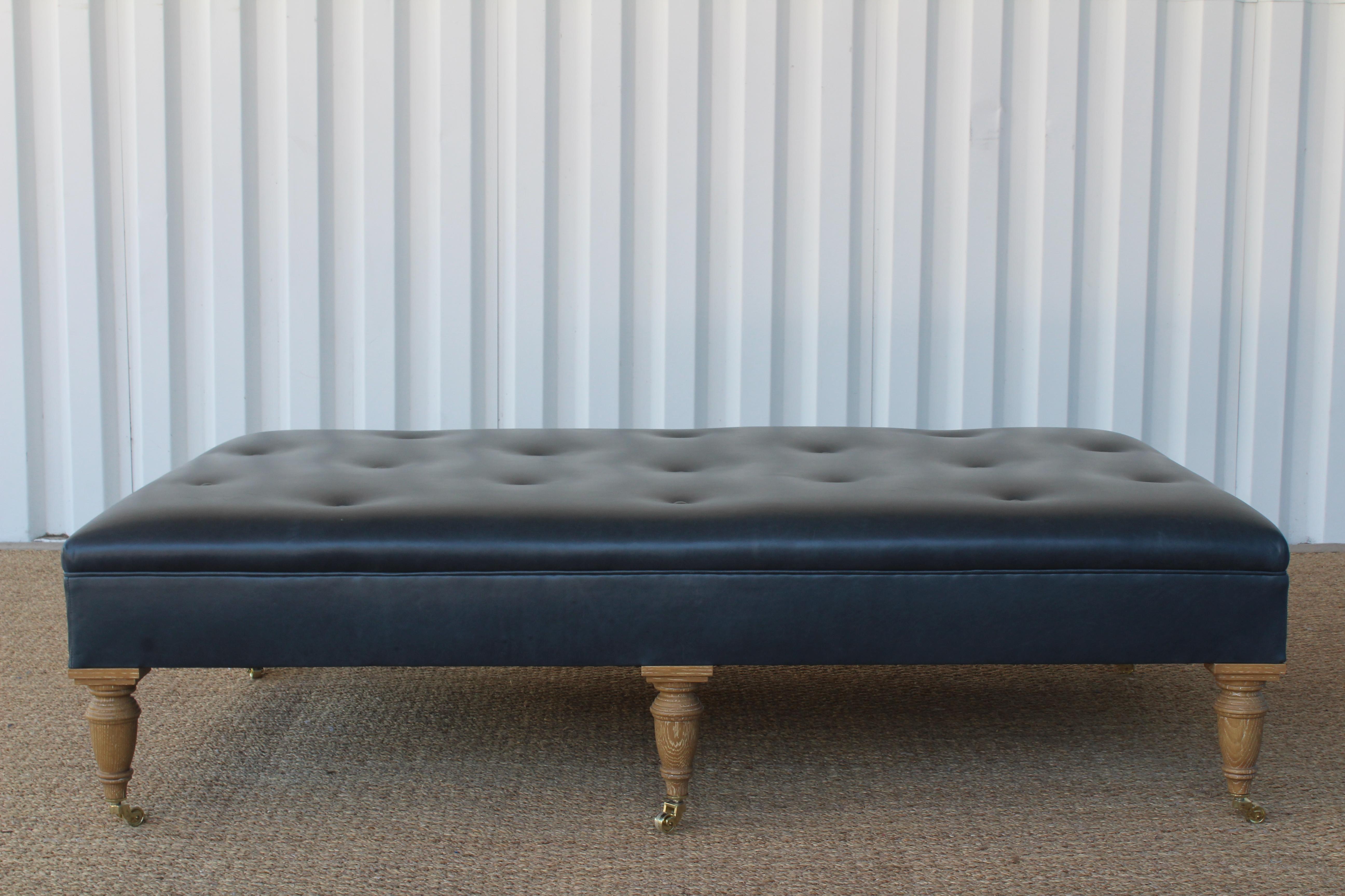 Custom Garner ottoman by Hollywood at Home. Tufted leather with cerused oak legs on brass casters. The leather shows minimal wear. Handmade in LA.