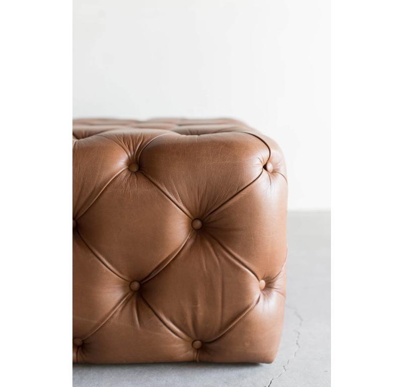 Le Design/One est une version classique du design. Fabriqué à la main avec soin, cet ottoman est doté d'un magnifique revêtement en cuir tufté dans une couleur caramel chaude, ajoutant une touche cossue à votre espace. La conception