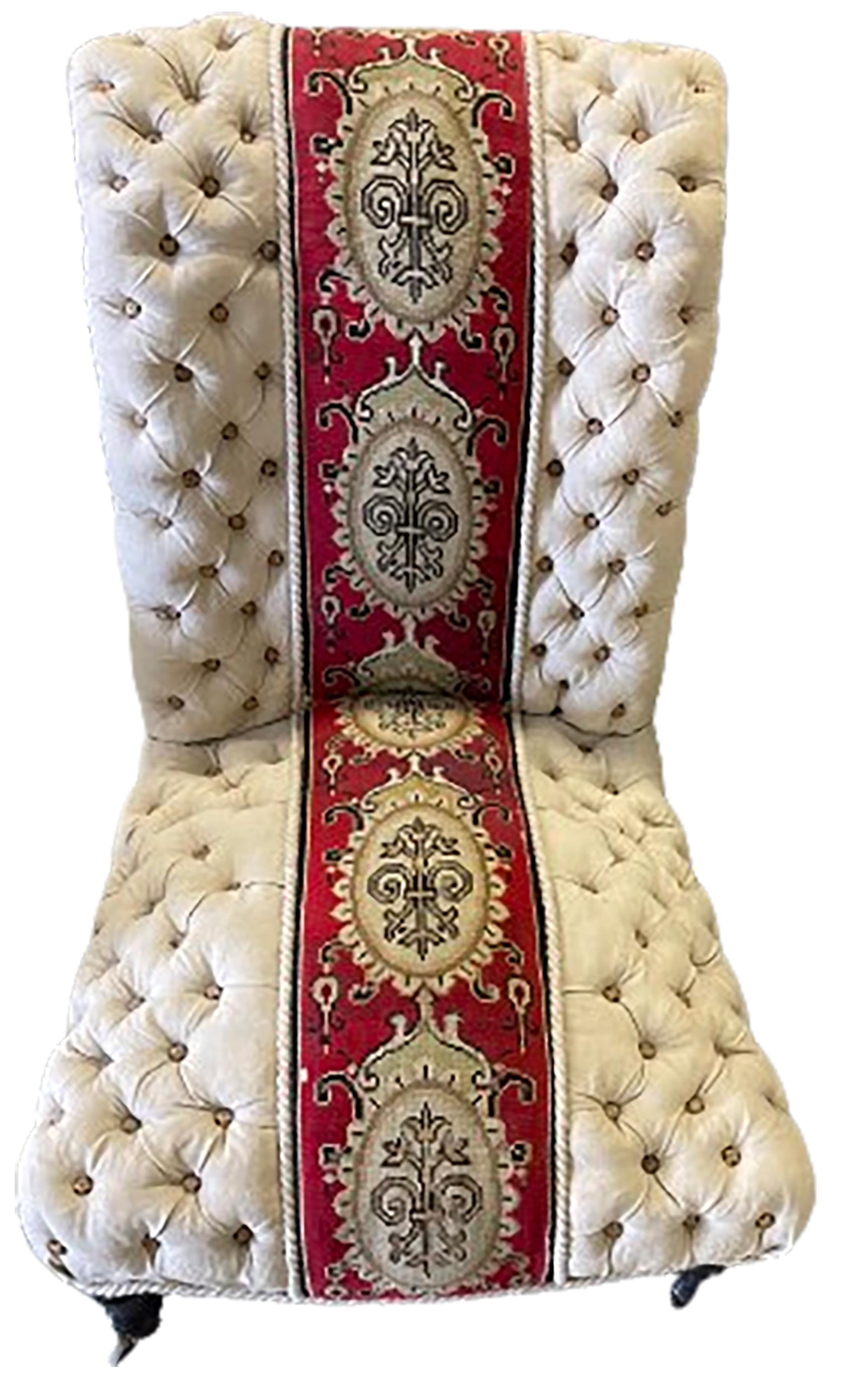 A handsome white tufted Napoleon III occasional slipper chair. Scrolled back with black painted wooden legs.  wheels on the front legs. Crimson red and white ornate needlework panel running from bottom to top. Solid color on the back.

No obvious