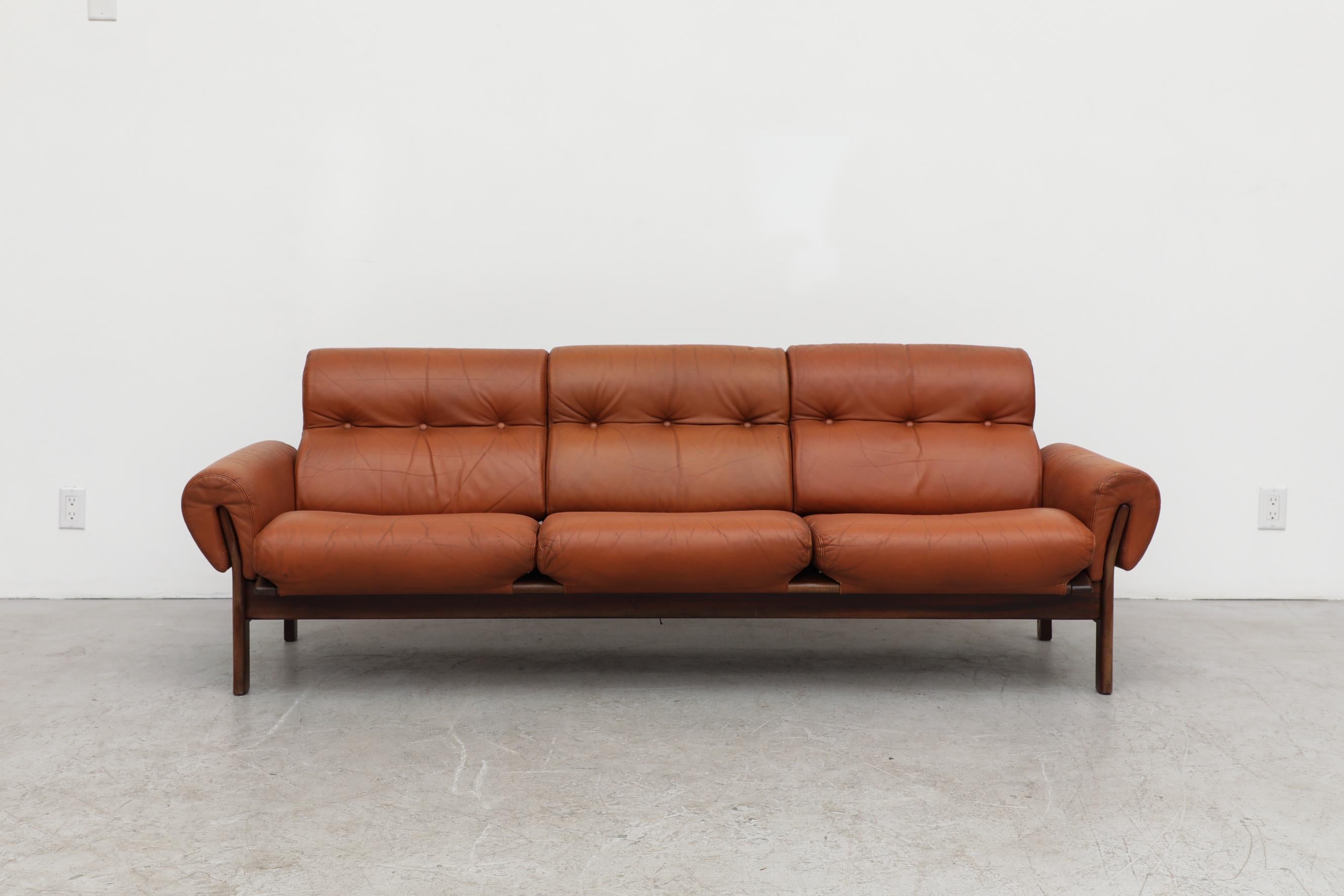 Handsome terracotta leather 3 seater sofa with a rosewood frame by Coja. In original condition with visible wear and patina on the leather, consistent with its age and use.