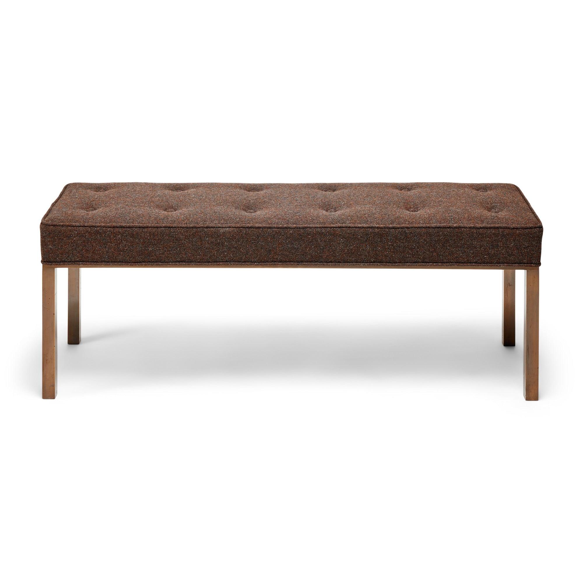 Una panca imbottita con struttura e gambe in bronzo.