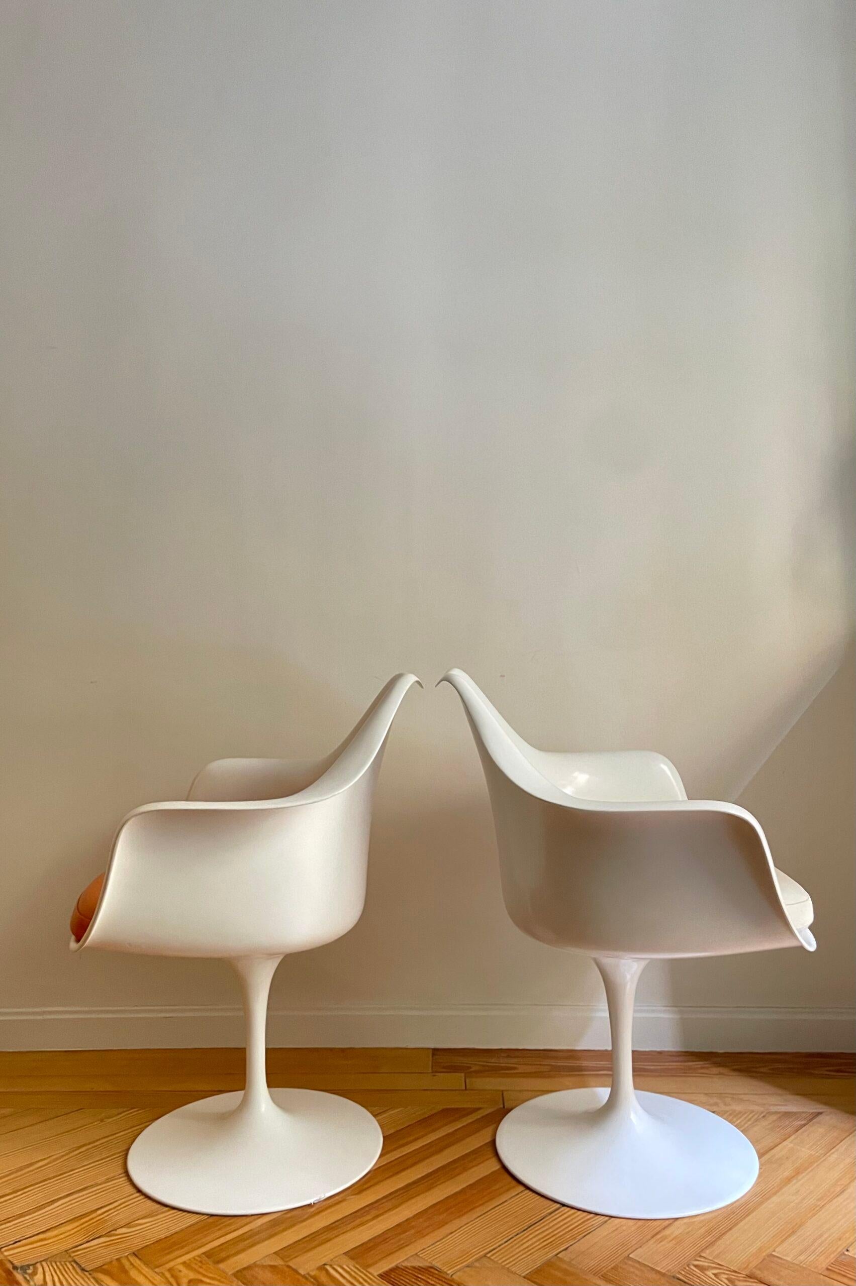 Tulip armchairs by designer Eero Saarinen produced by Knoll. The swivel base is in powder-coated cast aluminium and the seat shell is in moulded fibreglass. This design breaks the mould of the classic four-legged chair as does the material from