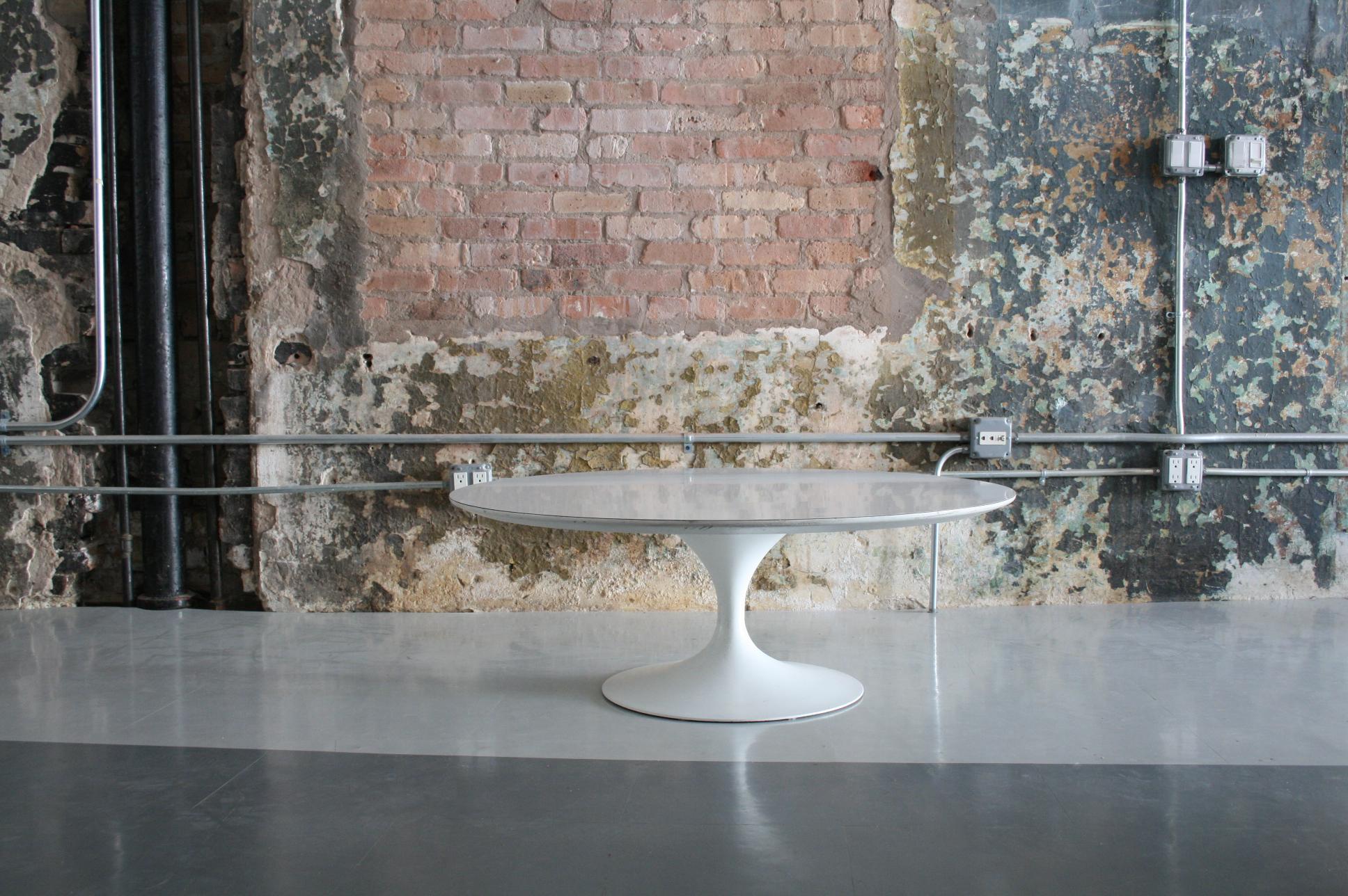 This is an early cast iron base Tulip coffee table by Eero Saarinen for Knoll. Additionally, the table features a white laminate top.
 