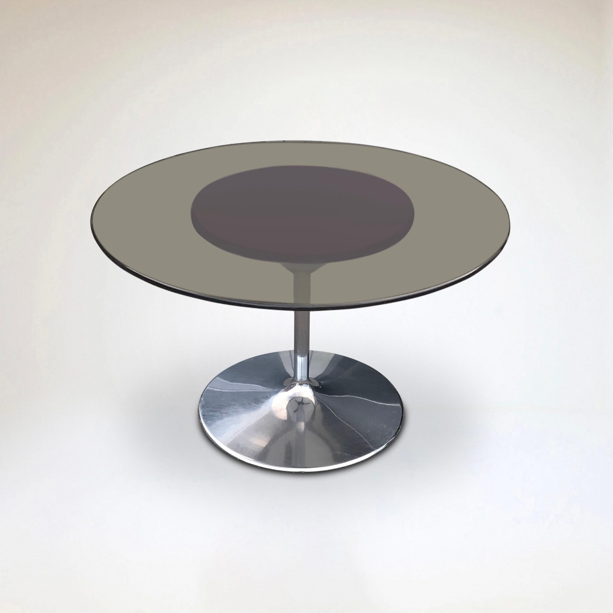 A rare Tulip dining table by Chromcraft USA in typical space age fashion.

Tulip shaped metal foot with a leather pad and a smoked glass top on top.

The top lays on a round brown leather surface, which provides enough friction to secure the glass
