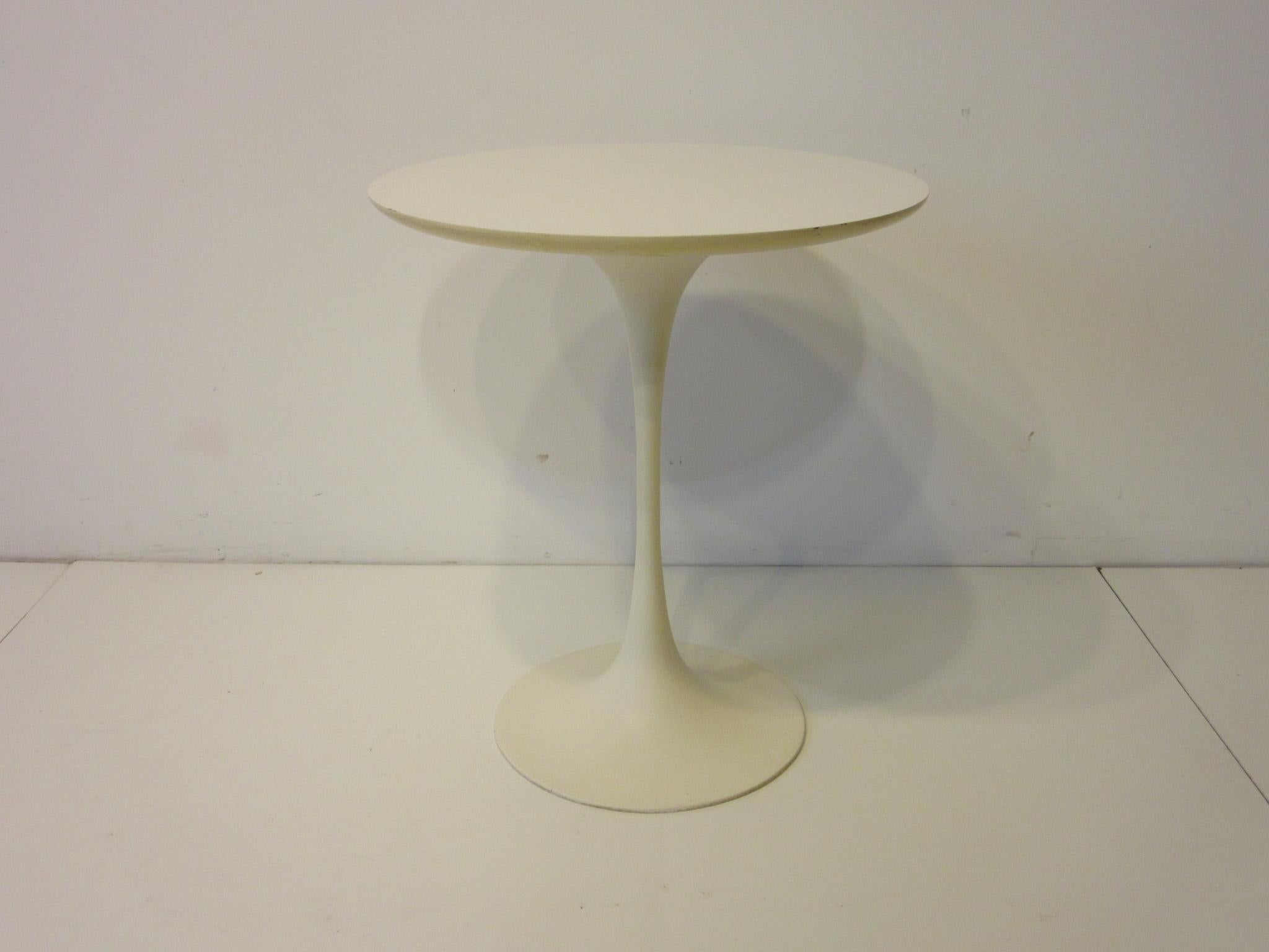 A tulip based pedestal side table with a satin white cast metal base and matching round laminate top designed in the manner of Eero Saarinen and Knoll, manufactured by the Burke Furniture Company.