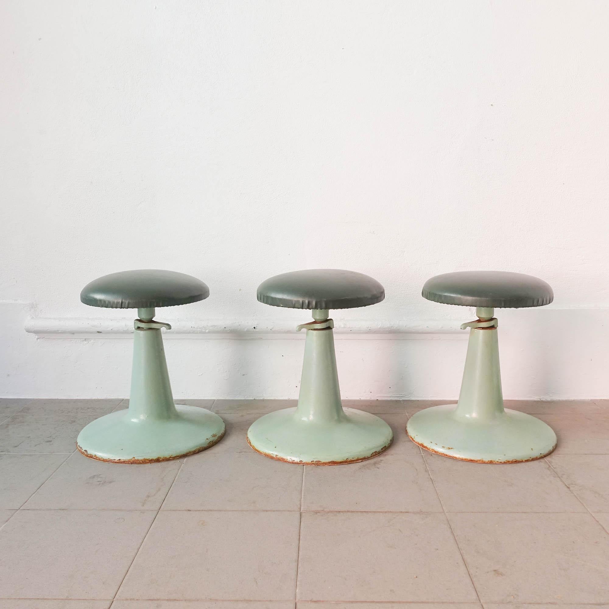 This stool was produced in United Kingdom during the 1950's and it belonged to a dentist office. It has a tulip shape cast iron base, painted in mint green and a dark green synthetic leather seat. In original and good condition. The price is per