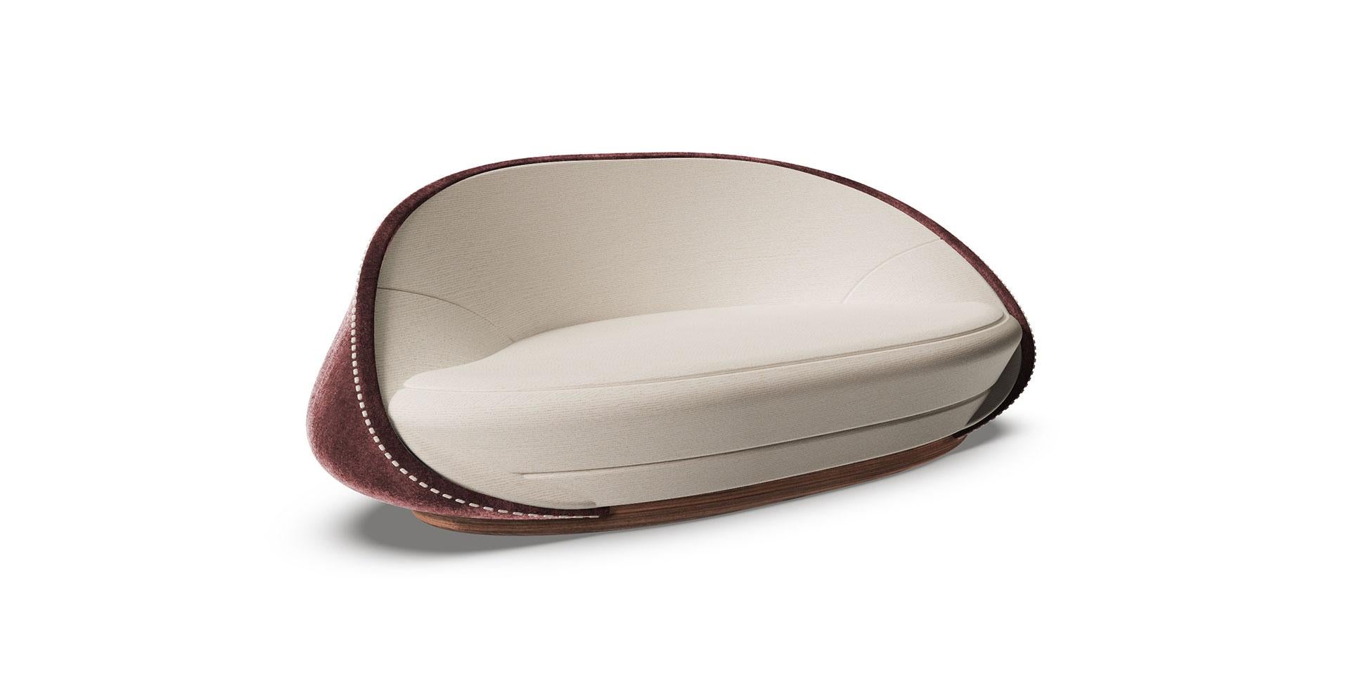 The design features a look based on the juxtaposition of colors: on one side there is deep color, which follows the curve of the enveloping backrest and on the other side there is the fabric of the cushions, with its haute couture feel.