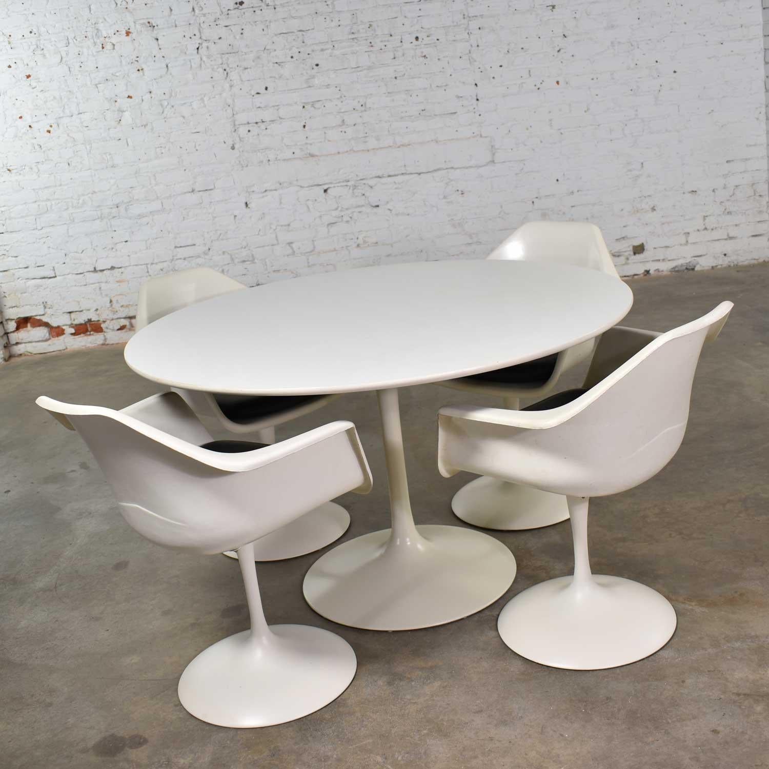 Handsome set of four tulip style white fiberglass swivel armchairs with black vinyl seat cushions and round dining table set by Arthur Umanoff for Contemporary Shells. These are era appropriate vintage chairs and table done in the style of Eero