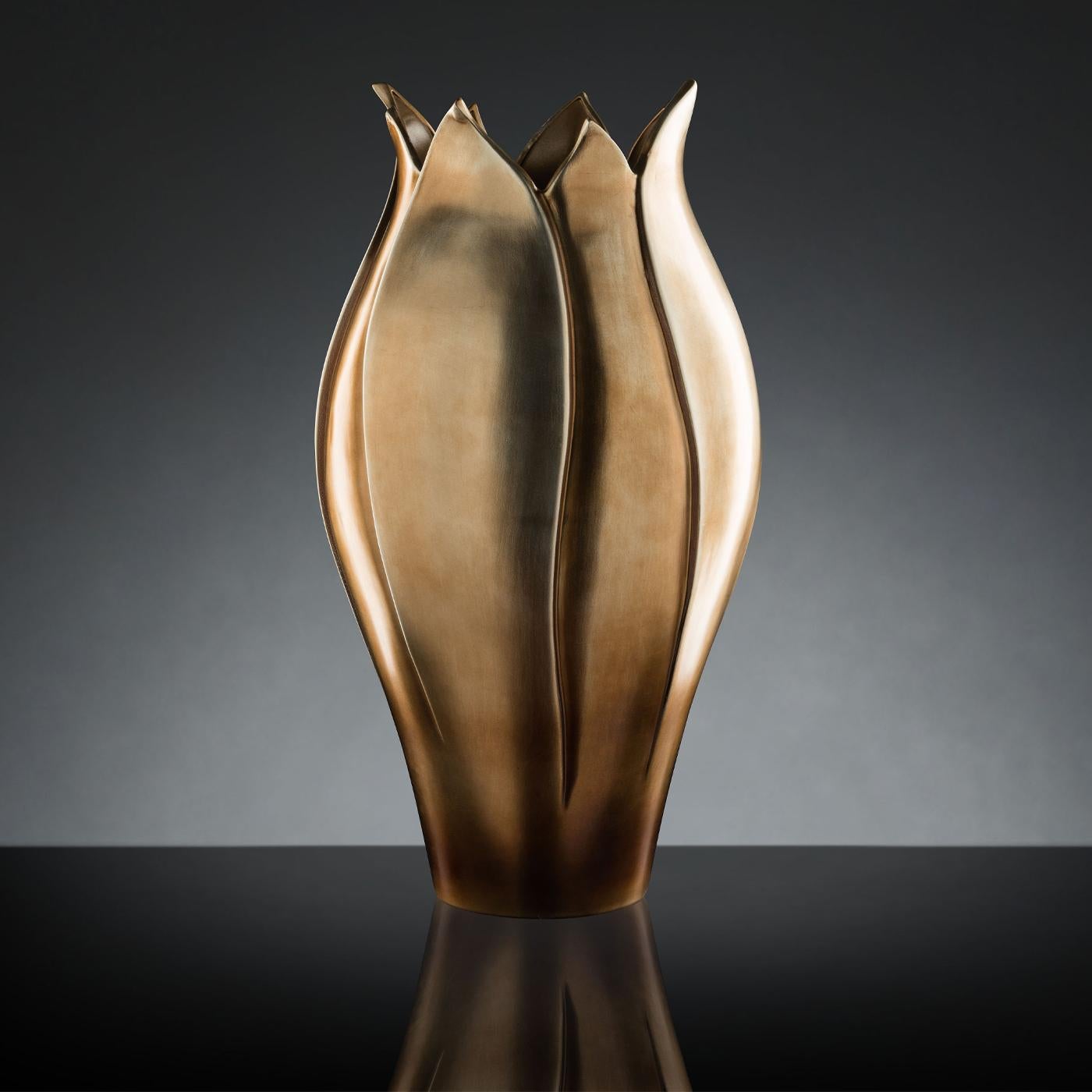 Sleek and refined, this vase exquisitely reproduces a tulip's bud. Boasting delicate and sinuous lines, it is handcrafted of ceramics showcasing an opaque and gleaming hue, reminiscent of brass' natural color. This vase will perfectly suit