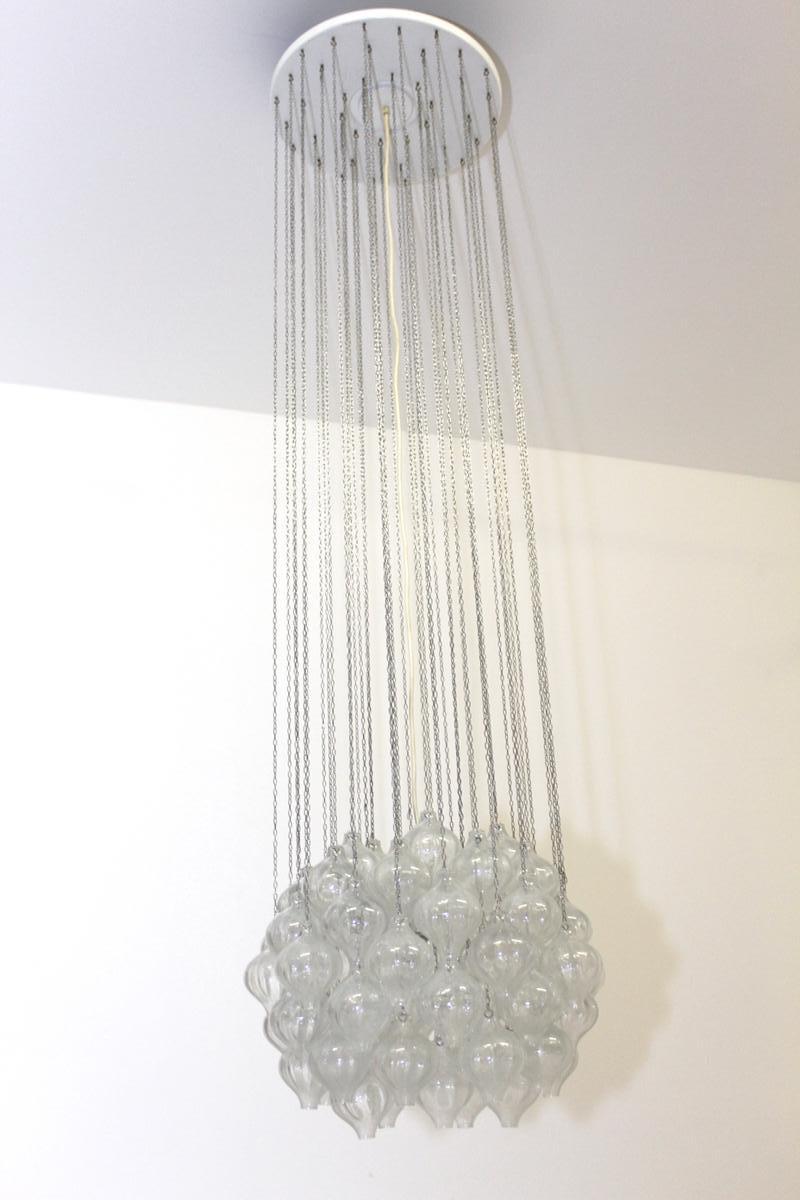 This piece features mouth-blown elements made of transparent glass with air inclusions, hung on chrome chains to form a spherical shape. It is an impressive, prestigious chandelier in typical 1960s design. All glass pendants are undamaged. The