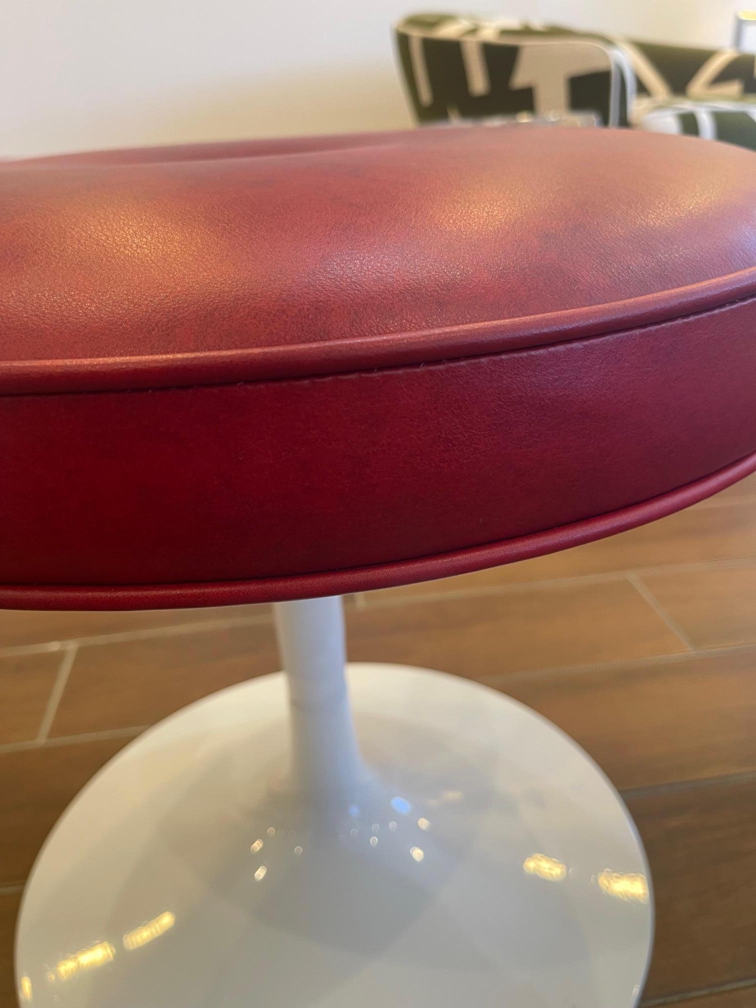 La otomana Tulip en piel rojo fuego es una versión moderna de un clásico muy querido. Con su estructura metálica y su suave cojín, es la pieza de acento perfecta.