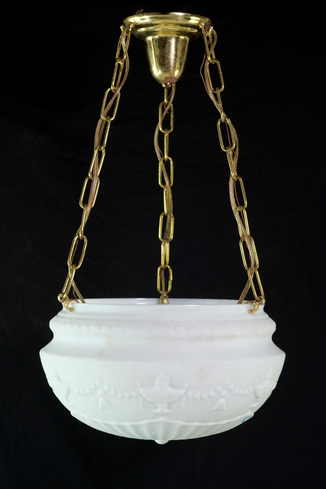 Antique fluted milk glass dish light detailed with embossed urns and tulip swag details. The polished brass hardware features a canopy with three wired chains supporting the dish light. The price includes restoration. This can be seen at our 400