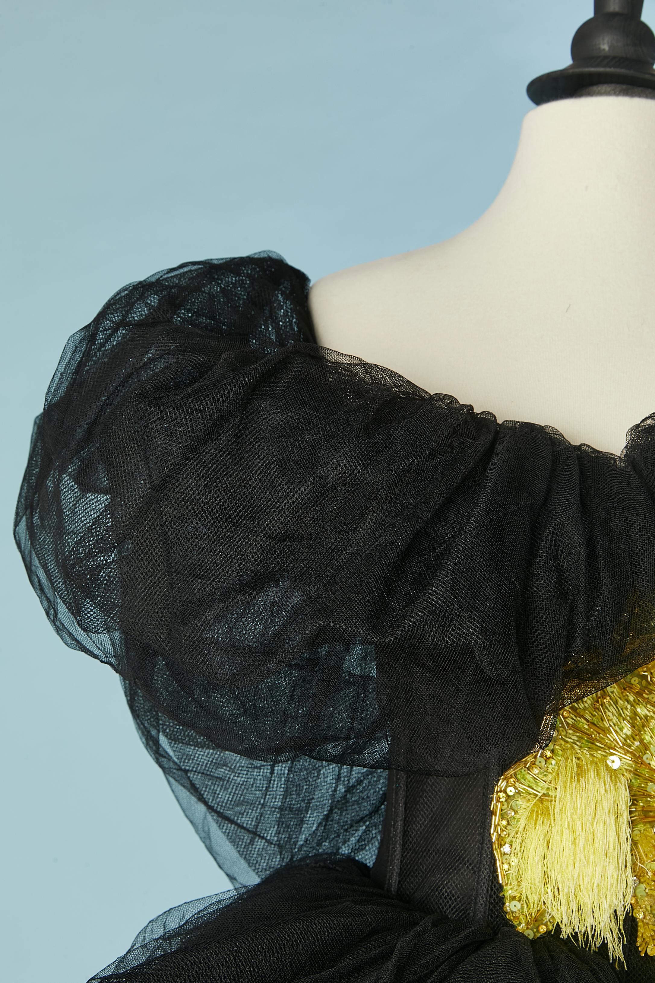 Abito da sera in tulle nero con ricami gialli. Composizione del tessuto principale: 100% poliammide. Ricami in seta. Bustier disossato. Plissettato e drappeggiato sul busto. Zip nascosta al centro della schiena. 
Paillettes e strass extra forniti.