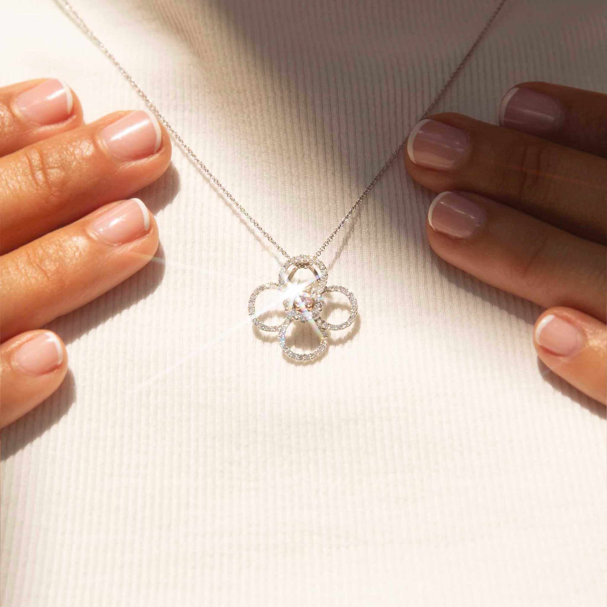 A blush of pink, a diamond's gleam,
A floral form, a precious dream.
A sparkling star, a radiant hue,
A masterpiece of jewelry, new.

The stunning Tullia Pendant & Chain features a captivating pink diamond set in the centre of an open-pattern flower