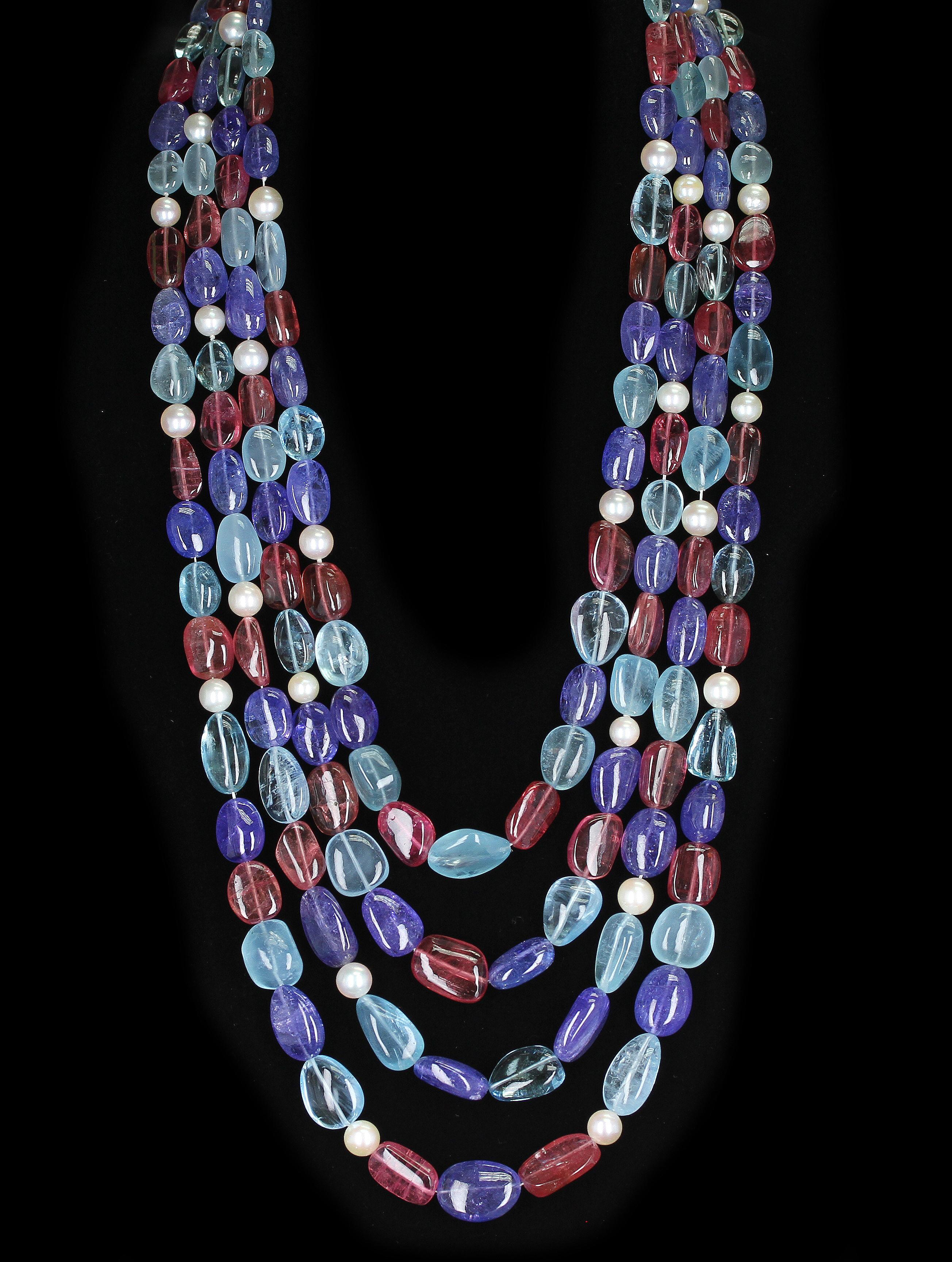 A candy-like three-strand necklace with smooth tumbled beads of Aquamarine, Tourmaline & Tanzanite with Pearls. The lengths of the strands range from 23