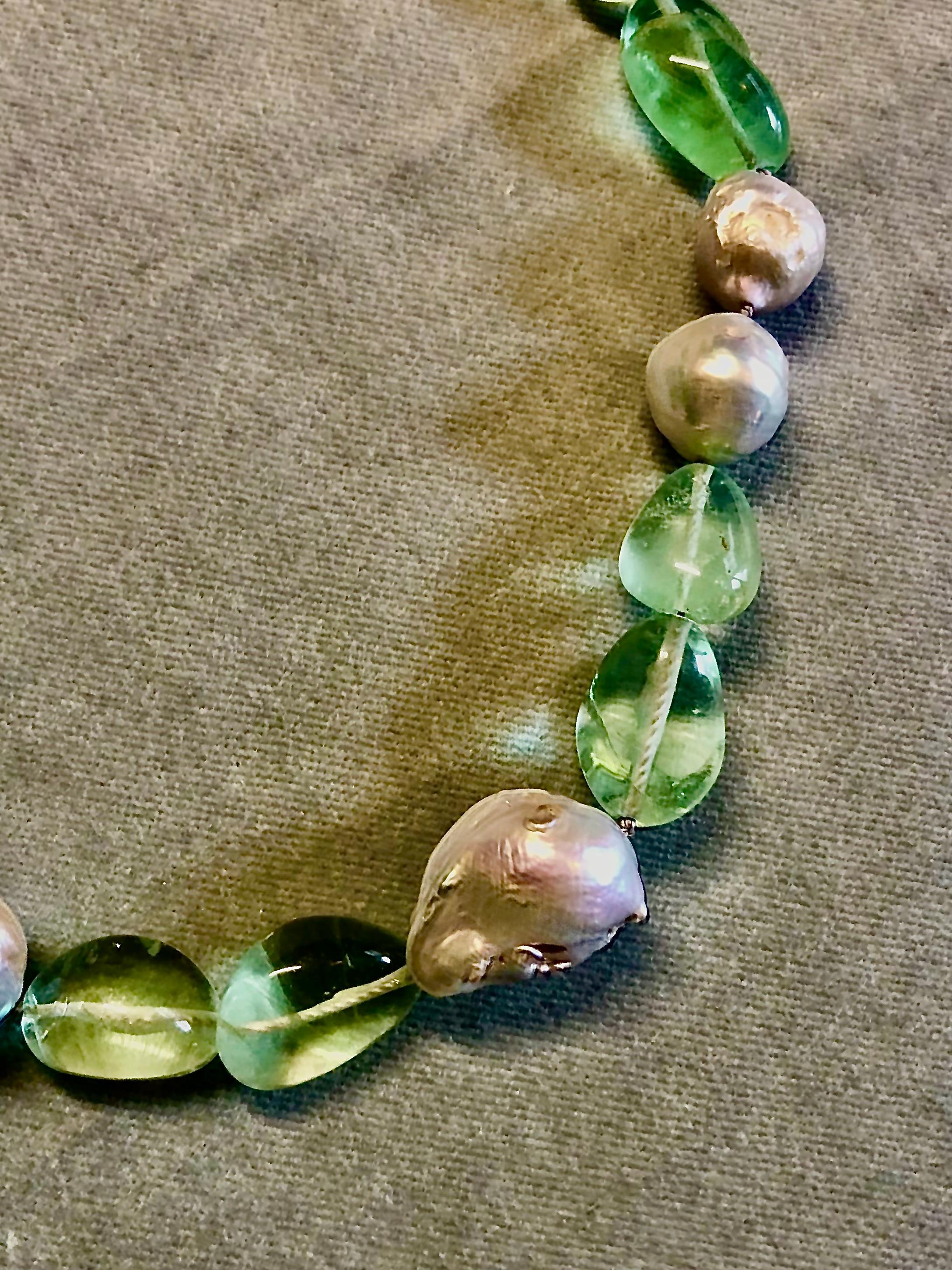Shimmering smooth tumbled fluorite nuggets with white round baroque crinkle freshwater large pearls. The strand is centered on a large white baroque freshwater pearl. Finished with macrame cord and abalone and sterling silver toggle clasp.