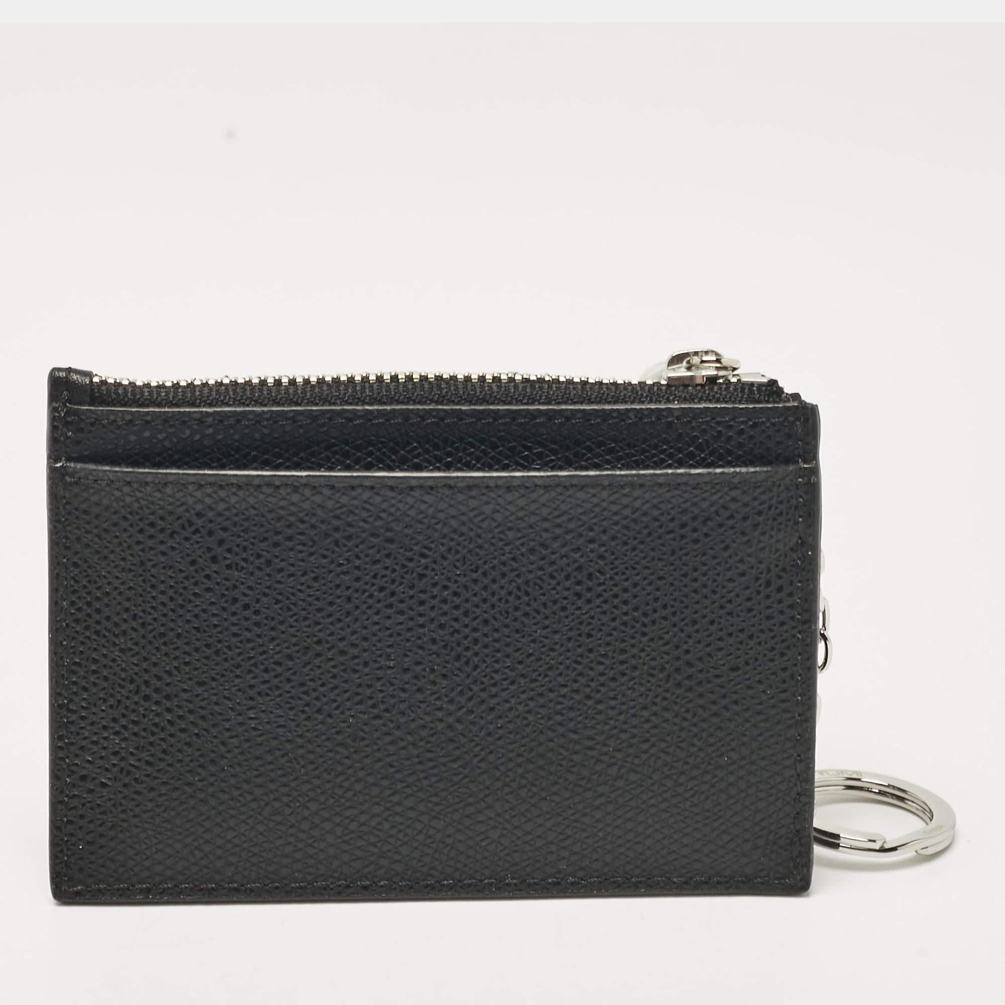 Realizzata in pelle nera, la Sinclair Slim Card Case di Tumi è elegante, sottile e pratica. Presenta una tasca frontale a fessura e una tasca posteriore a fessura, oltre a uno scomparto con cerniera che ospita un portachiavi con catena. Completa di