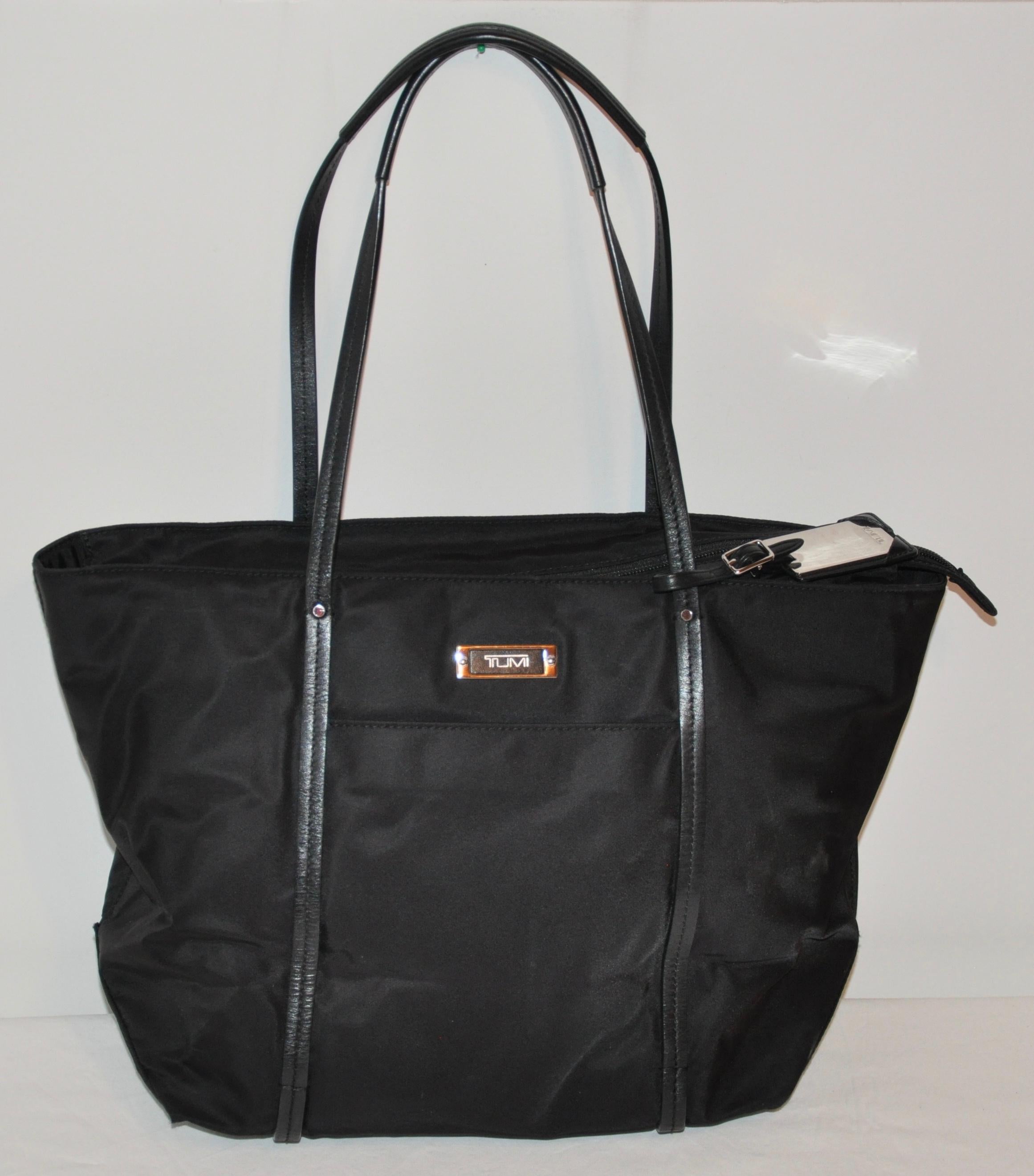      Tumi Black Nylon accented with black calfskin double handle tote measures 16 inches by 5 1/2 inches. Height measures 10 1/2 inch, the double handle straps measures 9 inches in height. Made in United States.