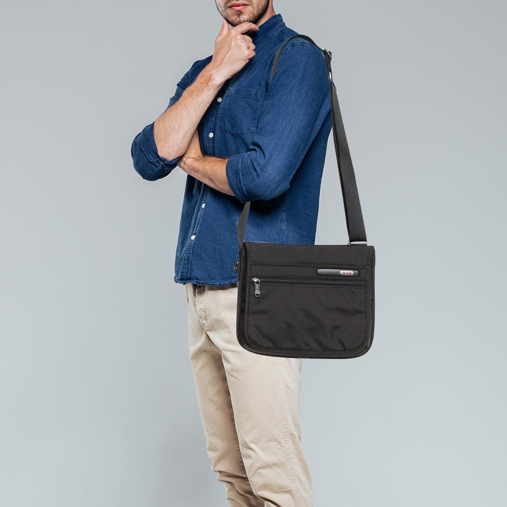 This messenger bag from Tumi is a reliable accessory. Crafted from nylon, the bag comes with a front flap that has a zip pocket and a brand logo detailing and opens to a nylon interior that houses two compartments. It is complete with an adjustable