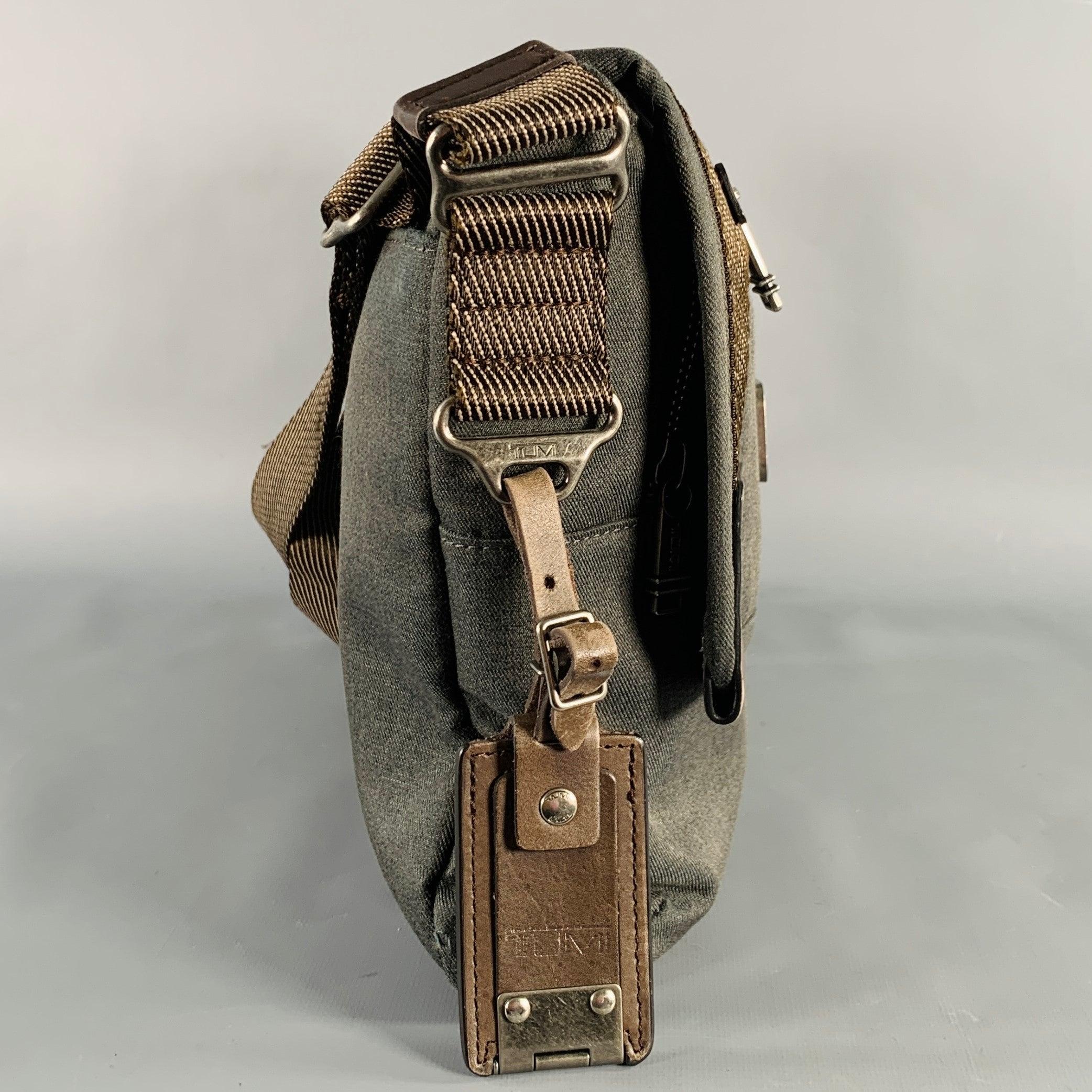 TUMI messenger bag
in a grey canvas featuring brown leather trim, adjustable crossbody strap, and magnet closure.Excellent Pre-Owned Condition. 

Measurements: 
  Length: 12 inches Width: 1.75 inches Height: 10.5 inches Drop: 14 - 28 inches 
  
  
