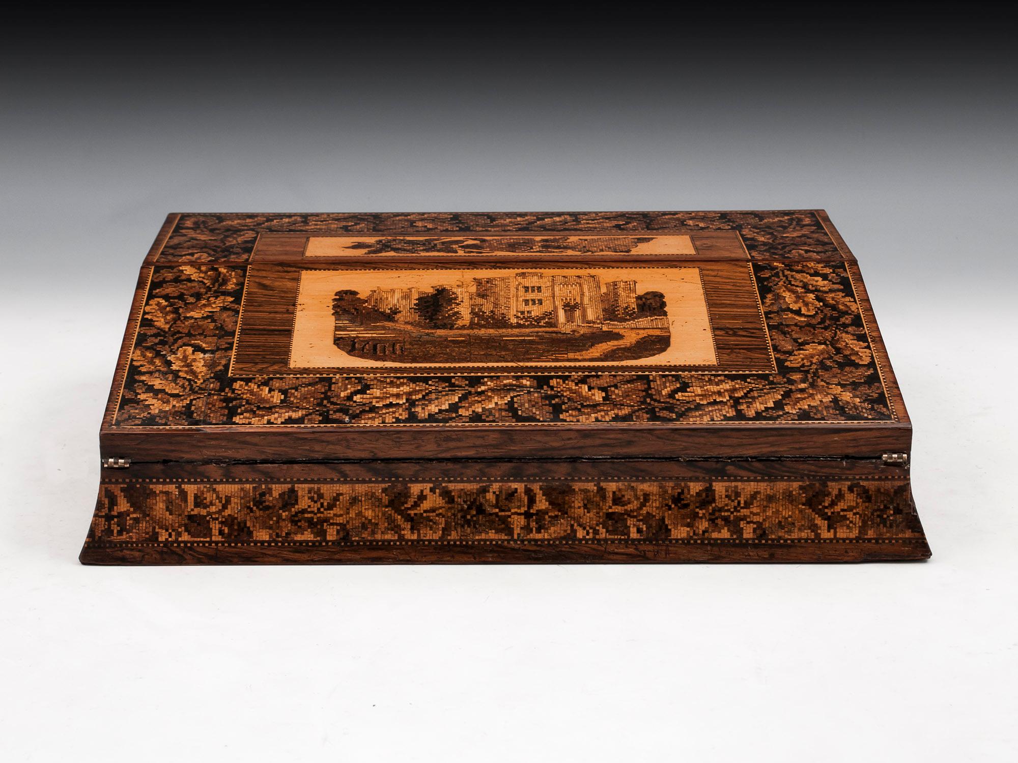 Tunbridge Ware writing box veneered in mahogany, with floral motif and view of Hever Castle, framed with an oak leaf border. Waisted sides. 

The interior of the Tunbridge ware slope is entirely original and comprises a tooled blue velvet writing