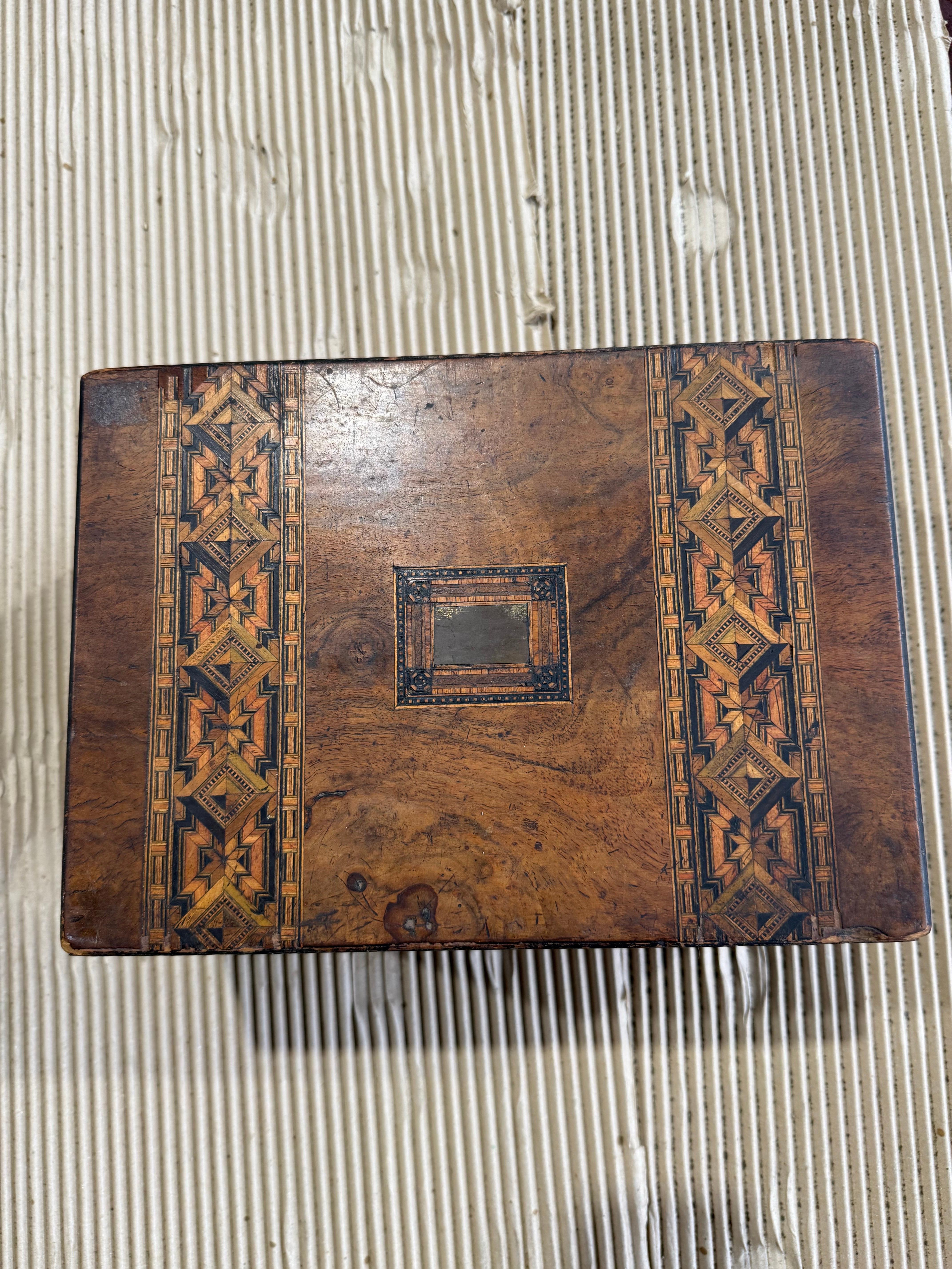 A finely crafted 19th-century Tunbridge ware box, showcasing the intricate geometric marquetry for which the style is celebrated. Made from richly figured walnut, this charming piece features decorative inlaid panels on the top and sides, composed