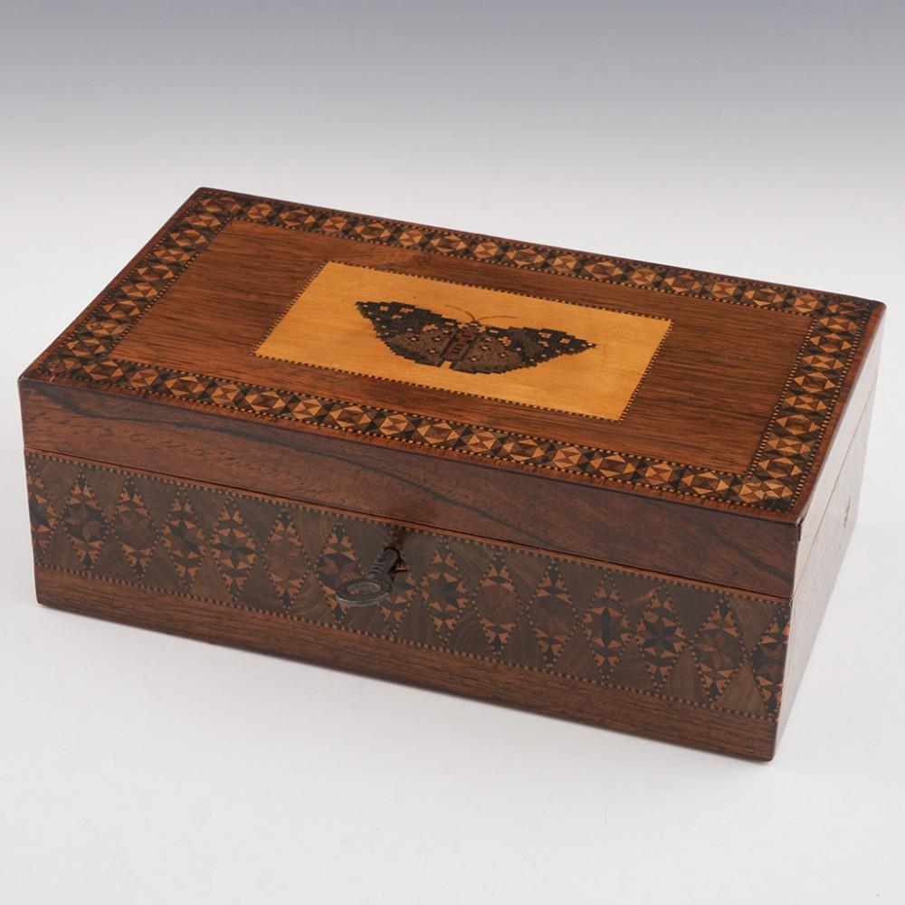Heading : Tunbridge ware rosewood box
Date : c1840
Period : Victoria
Origin : Tunbridge Wells, Kent
Decoration : Mosaic image of a butterfly within keylines. Geometric marquetry border. Side panels decorated with a broad band of stickware