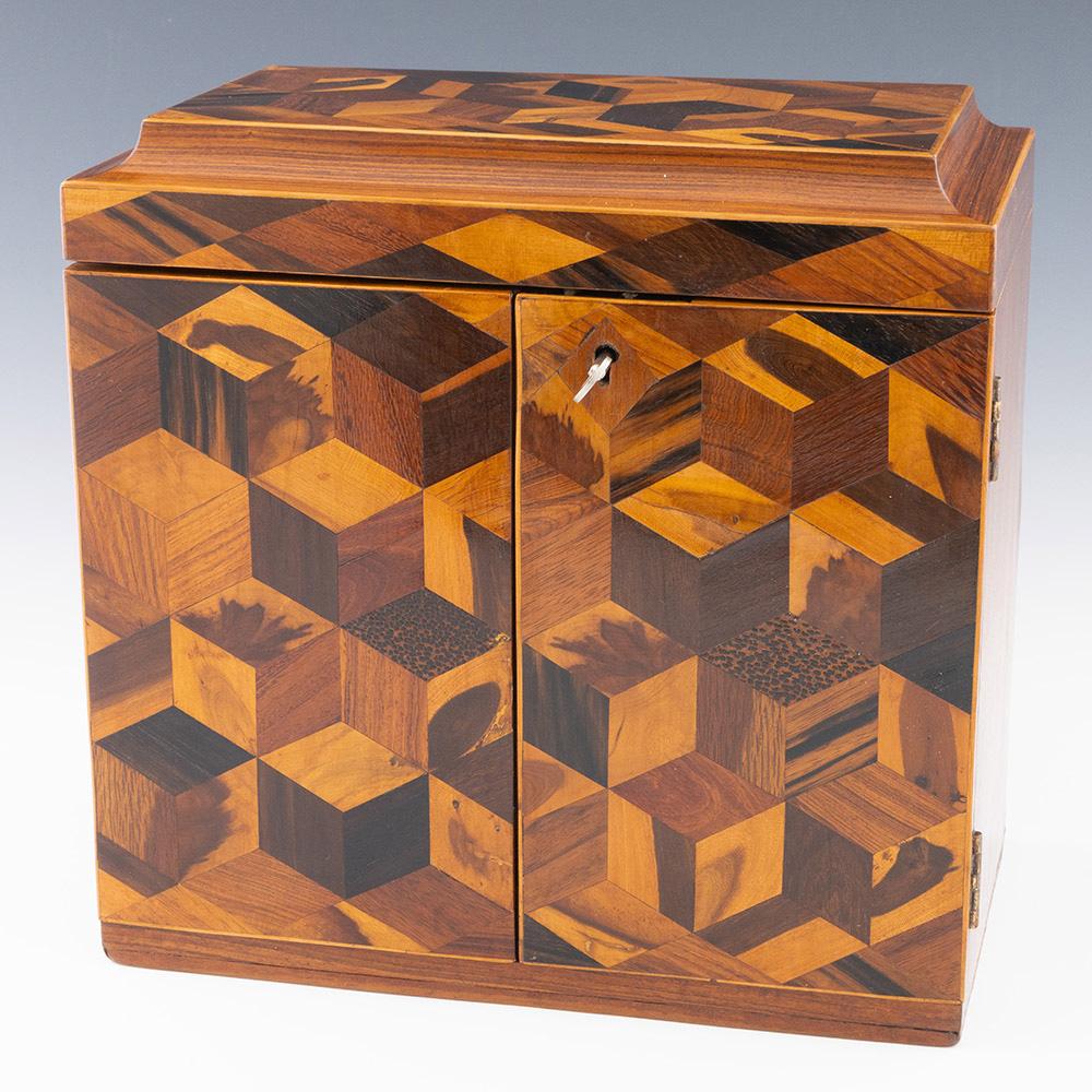 Encabezamiento : Armario de costura Tunbridge Ware con cubos en perspectiva

Fecha : c1840

Periodo : Victoria

Origen :Tunbridge

Decoración : Cubierta y puertas dobles decoradas con cubos en perspectiva. La tapa del cavetto se levanta para revelar