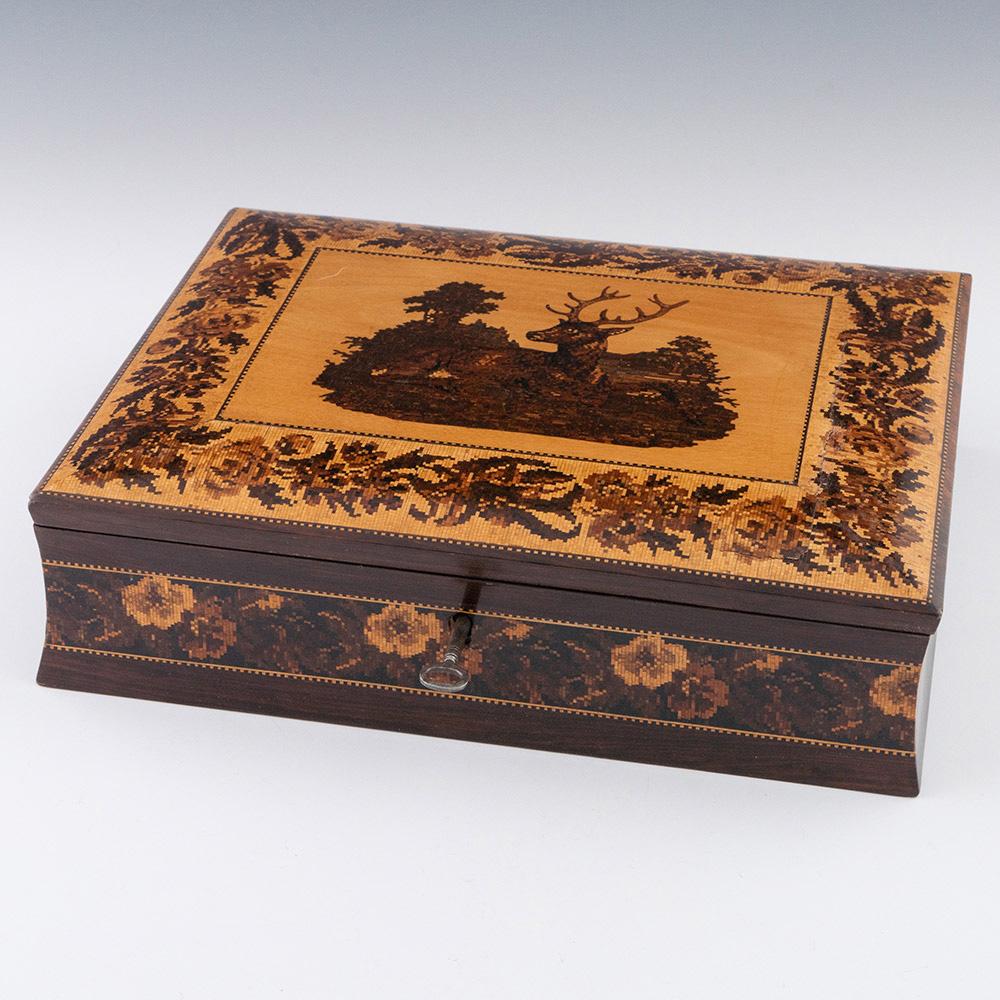 Überschrift : Tunbridge ware Schreibwarenbox mit Schreibschräge

Datum : c1860

Zeitraum : Victoria

Herkunft: Tunbridge Wells, Kent

Dekoration : Zentrales Bild eines Hirsches, florale Bänder in der Bordüre und Zackenleisten. Seitenteile mit