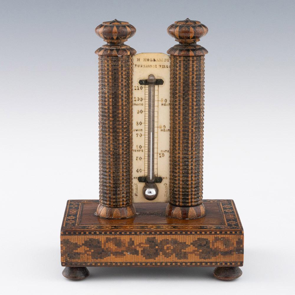 Heading :Tunbridge ware thermometer by Henry Hollamby.

Date : c1860

Period : Victoria

Origin : Tunbridge Wells, Kent

Decoration : Two pillars with stickewear tops and bases flank the thermometer which is labelled H Hollamby Tunbridge Wells. The