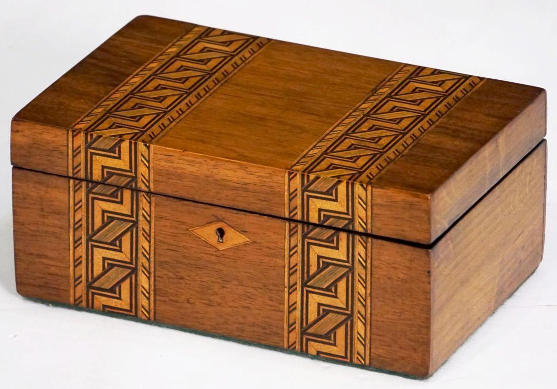 An English rectangular box featuring an inlaid design of miscellaneous woods known to collectors as Tunbridgeware.

Exterior with a geometric pattern design of herringbone to the top and front. 
With diamond inlay to the escutcheon.

The hinged