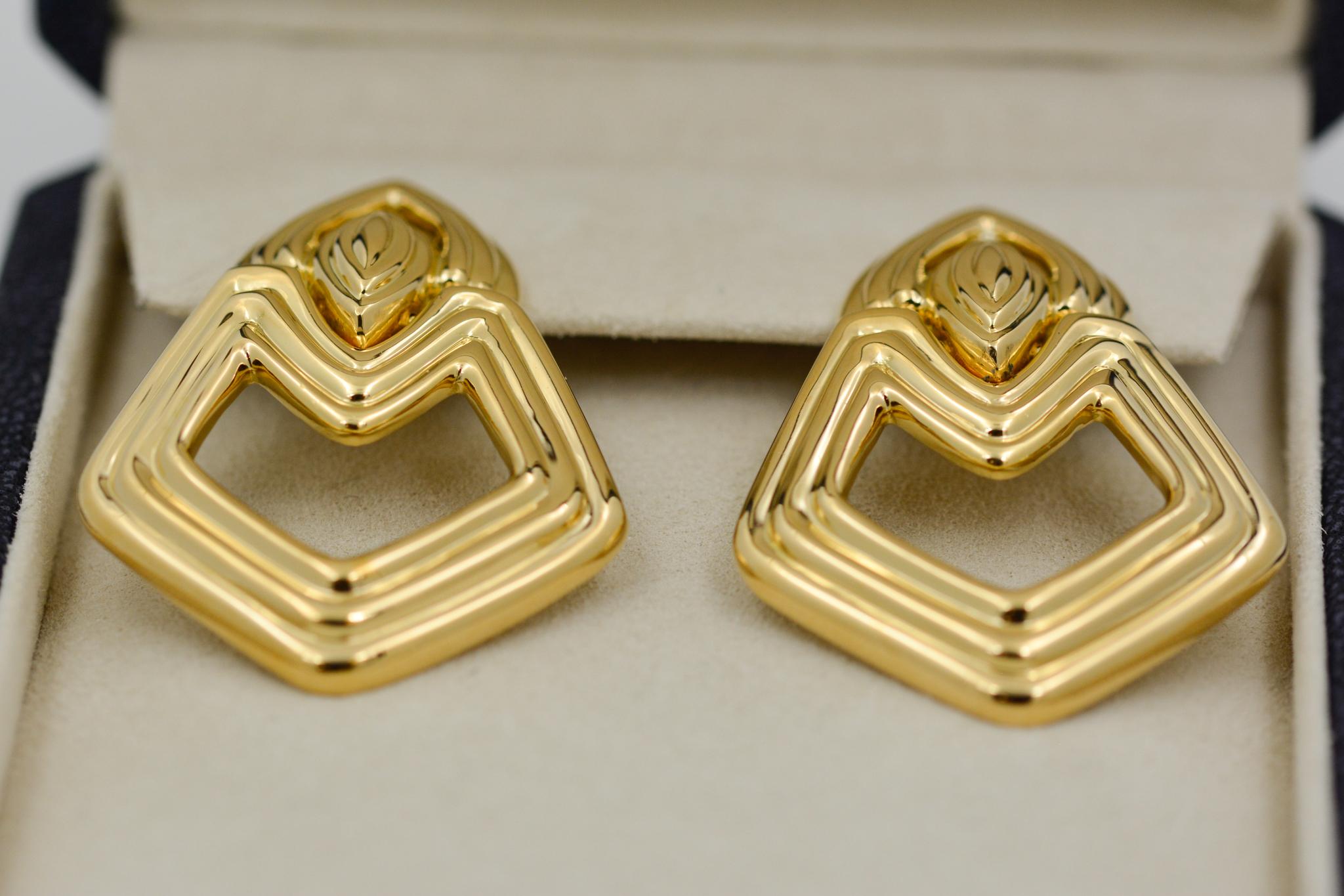 These 18 karat yellow gold earrings from Turi are crafted in a door knocker design with a high polished ribbed finish and have omega post backs. 