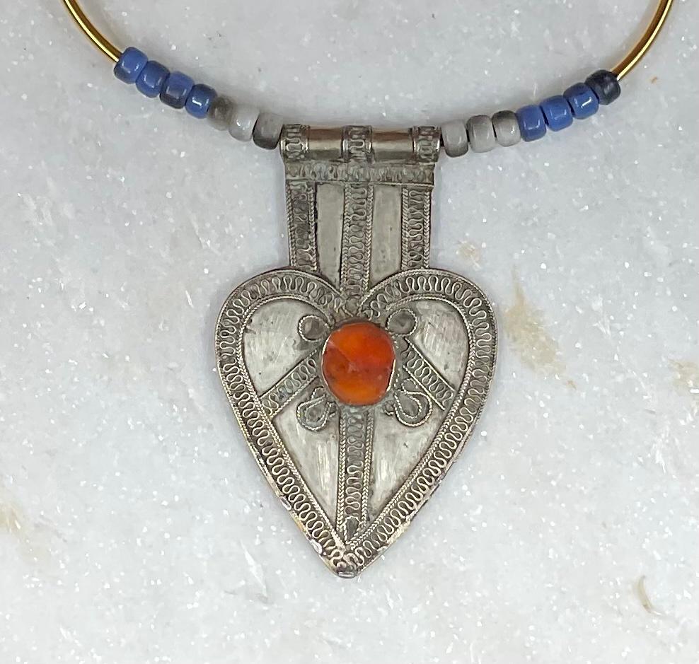 
Tribal jewelry vintage chocker , leather strap with colorful glass beads . the main object artistically  hand made from silver and brass with one piece of glass embedded in the center.
Exceptional object of art to hang .