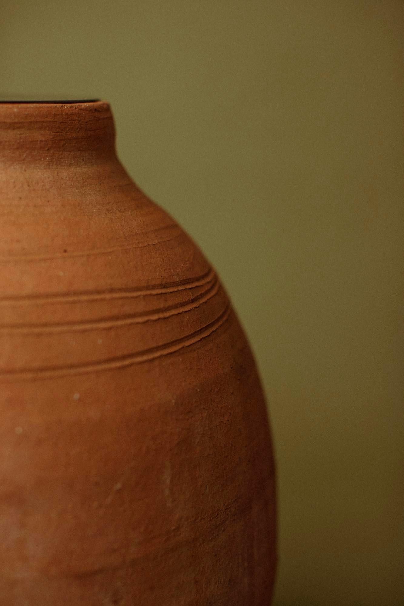 Cette lampe de table en terre cuite du XXe siècle a été formée en Anatolie à partir d'argile locale dense, puis cuite à la fumée pour obtenir une patine rouge terre intense, évoquant les paysages d'argile brûlés par le soleil de la Méditerranée.