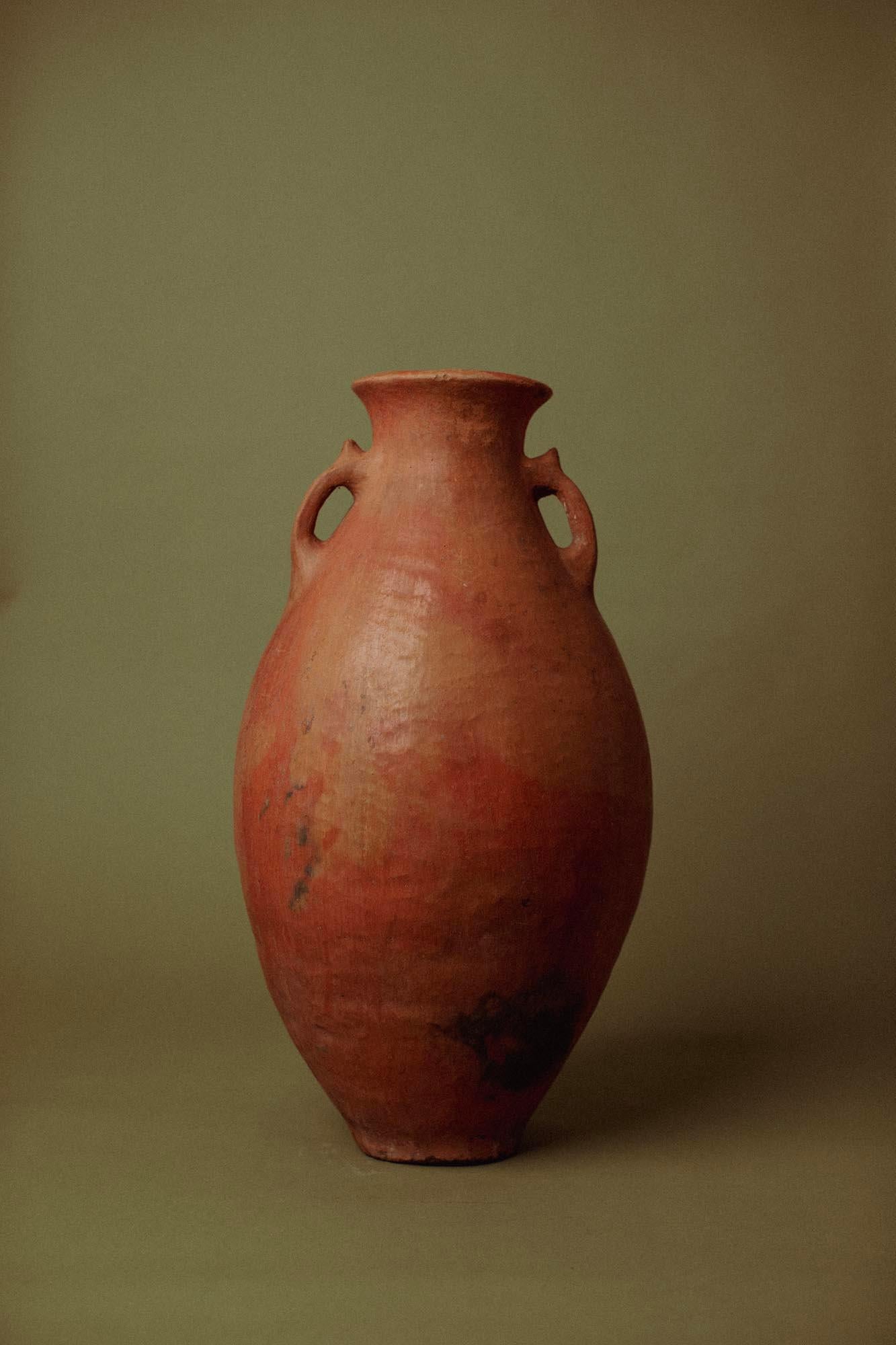 This 20th-century hand-crafted terracotta olive jar originates from Anatolia, where field firing — an open-air kiln method — produced vessels with richly varied tones and natural smoke patina. The piece was traditionally used for olive storage, its