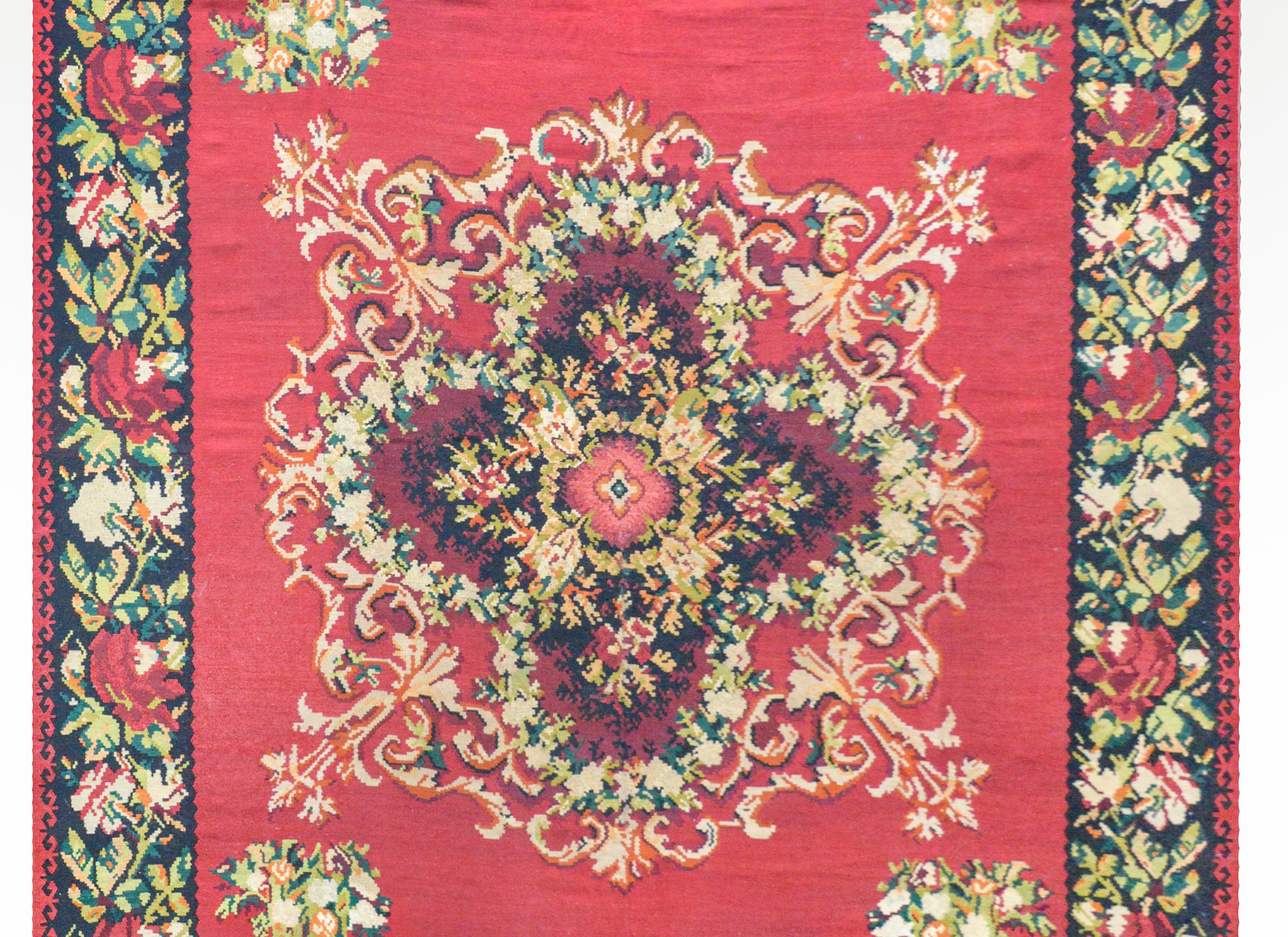 A bold vintage Turkish Bessarabian Kilim woven with a large central floral medallion woven in light and dark crimson, light and dark green, white, orange, and black wool, against a solid crimson ground. The border is wonderful with a floral pattern