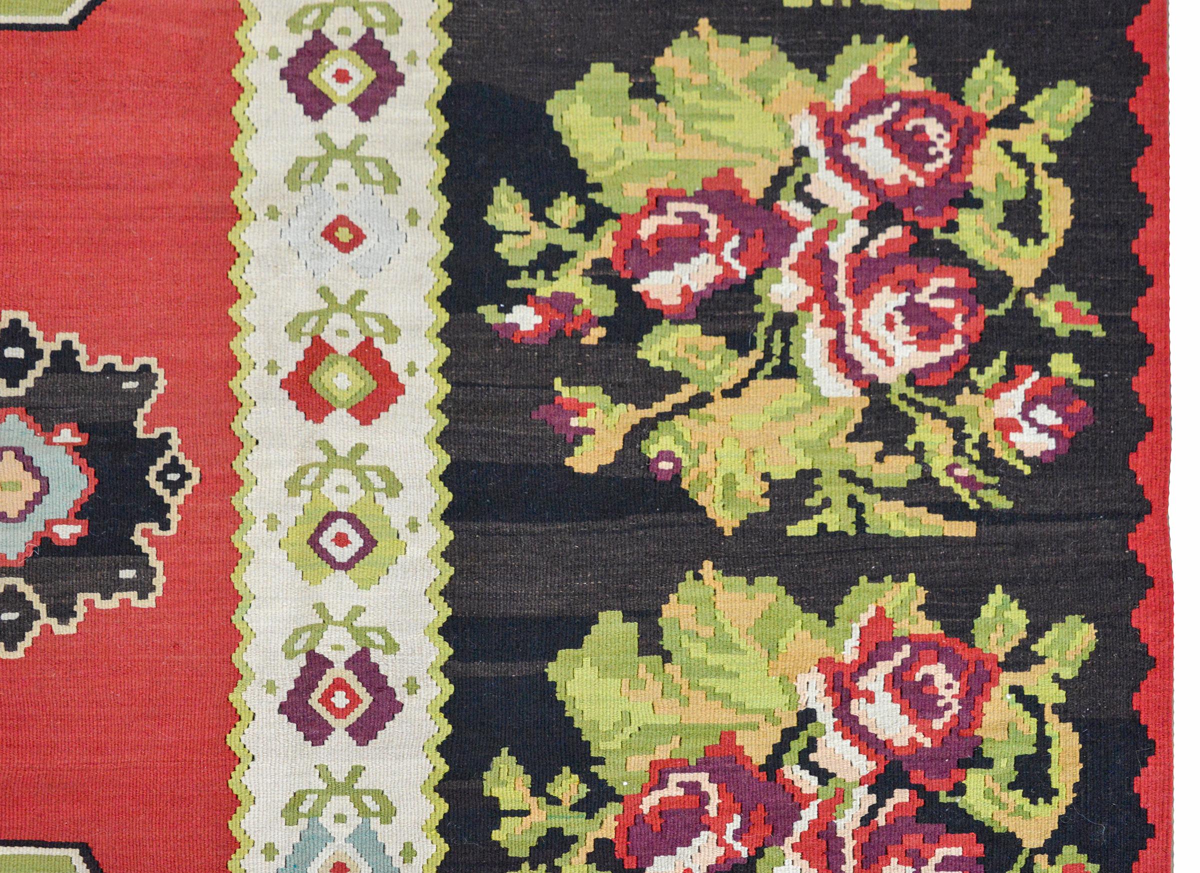 A bold Turkish Bessarabian Kilim woven with two large central stylized floral medallion woven in light and dark green, black, white and pale indigo, against a crimson ground. The border is wonderful with a wide outer large-scale floral pattern and a
