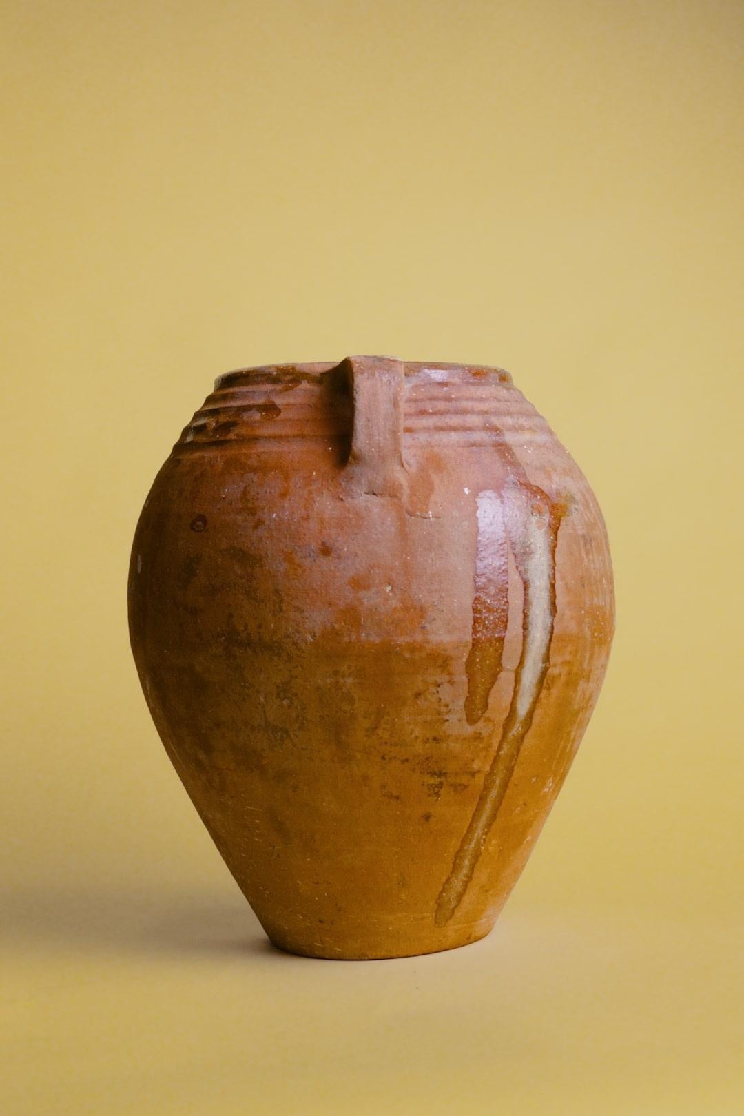 Questo vaso turco a doppio manico in terracotta è un pezzo accattivante che incarna l'eredità e la maestria dell'artigianato anatolico. Con la sua forma robusta e i doppi manici elegantemente curvati, questo vaso vintage in argilla è stato