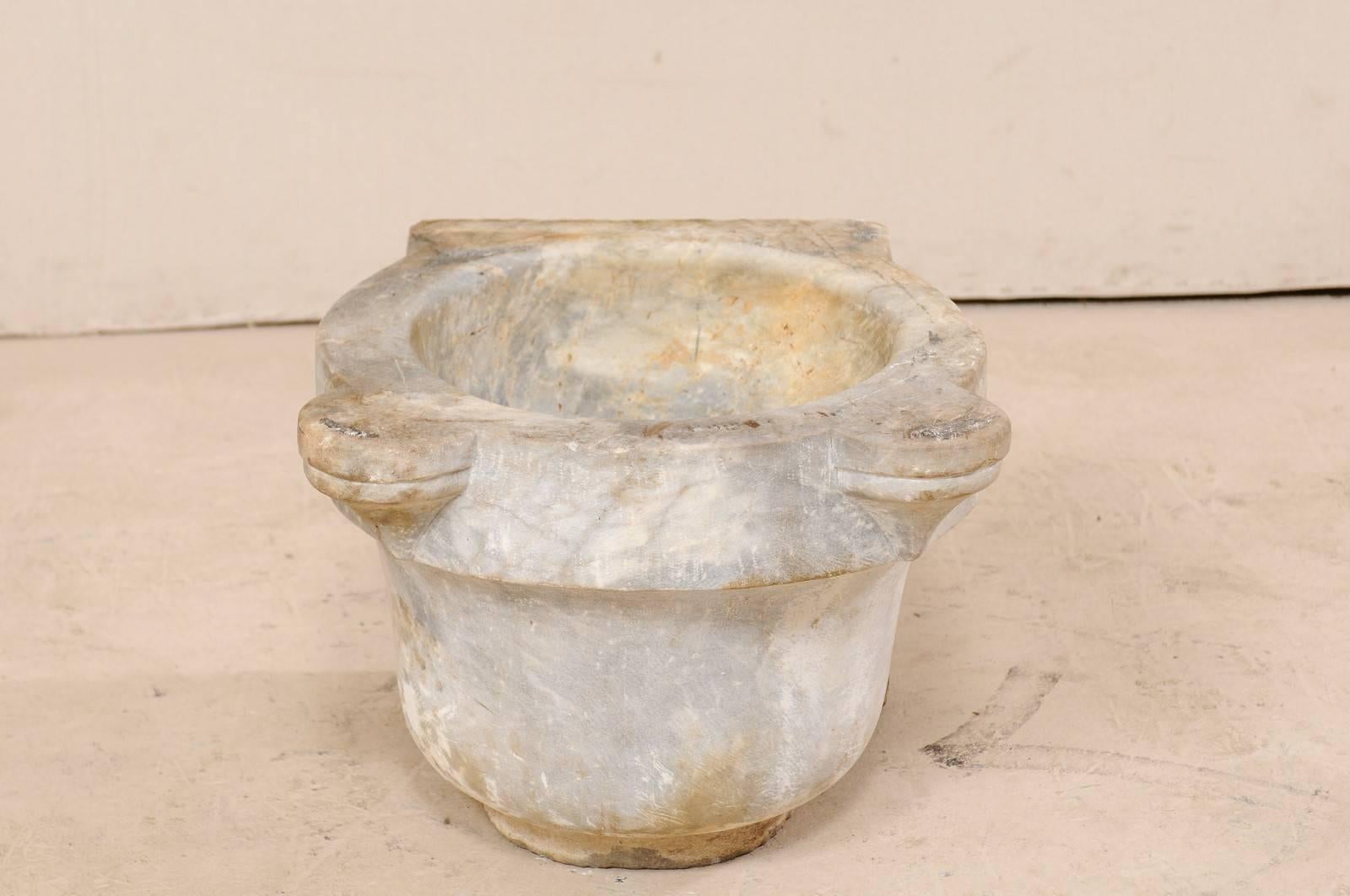 A Turkish hammam wash basin of marble from the 19th century. This antique hand-carved marble basin was once used within a Turkish bath house or hammam. The backside of the basin remains flat, allowing it to be placed flush against a wall. Aside from