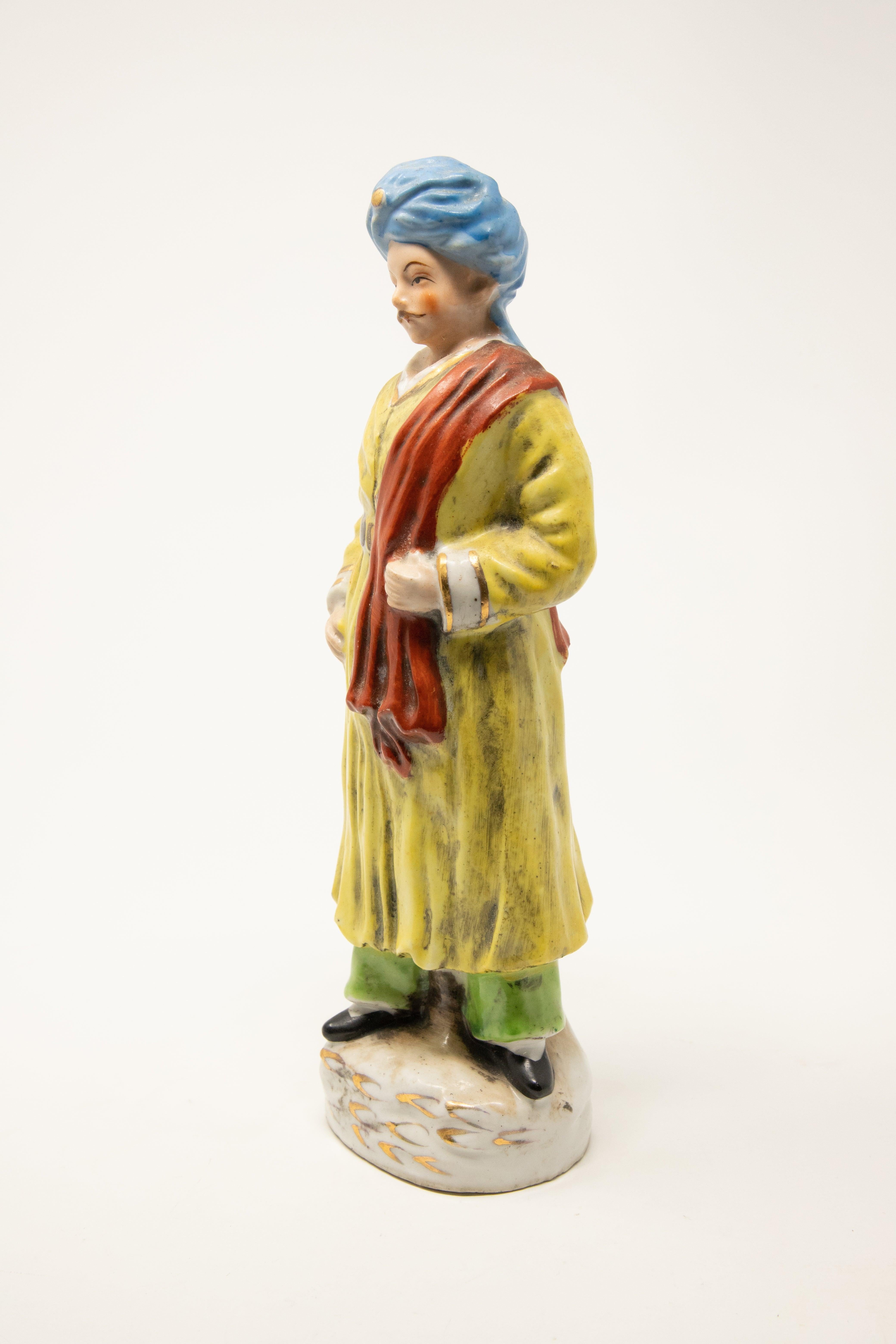 We are offering a Turkish-inspired figurine. This piece depicts the likeness of a man dressed in Ottoman Empire-style garments in shades of blue, green, yellow, red, and gilt. It is labeled “Hand painted, Japan” to the underside.