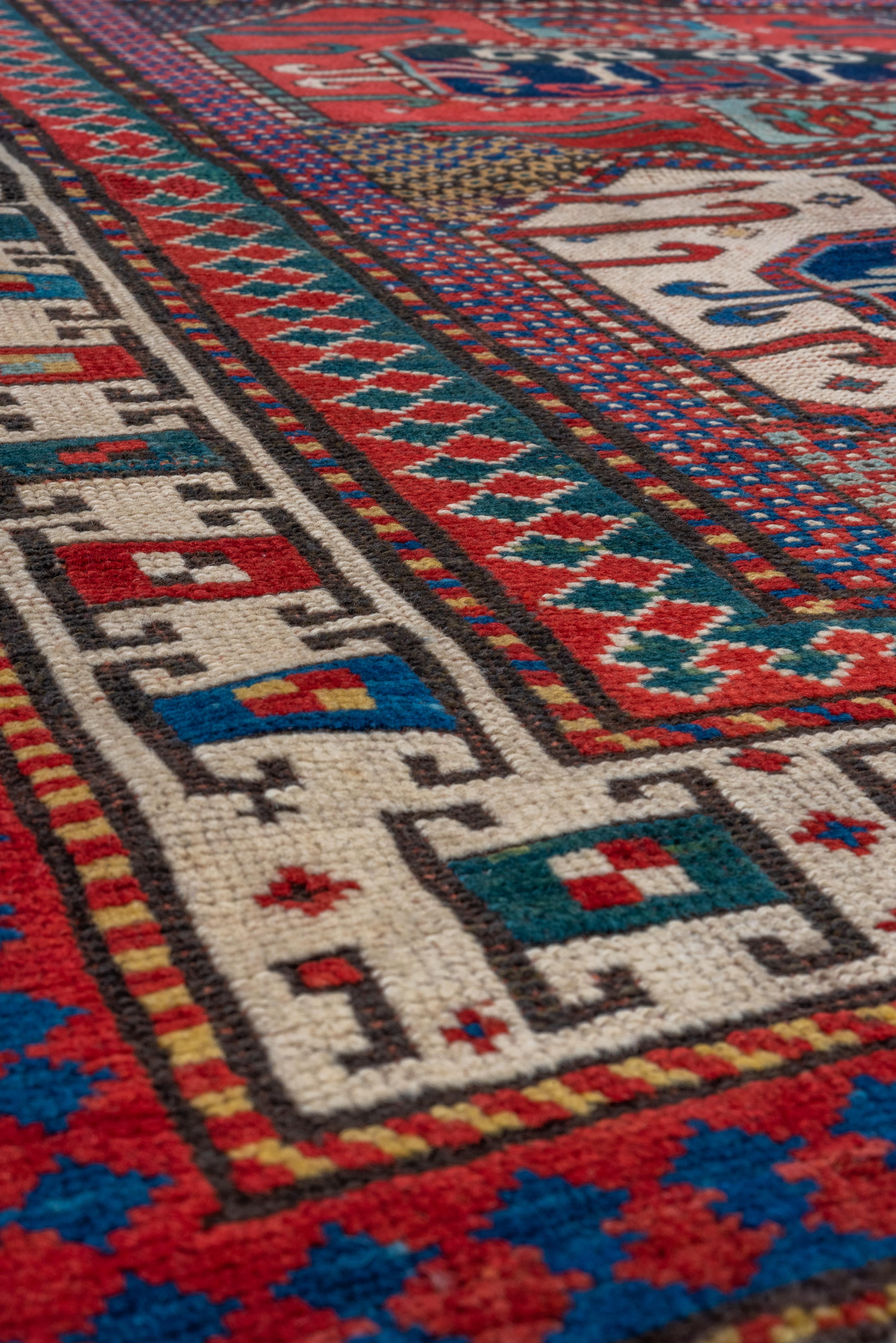 Dieser Kazak-Teppich (4,0 x 4,7) ist ein Beispiel für die kühnen geometrischen Muster und lebendigen Designs, für die die kaukasische Weberei bekannt ist. Die zentralen Motive, die von komplizierten Bordüren umrahmt werden, spiegeln das reiche