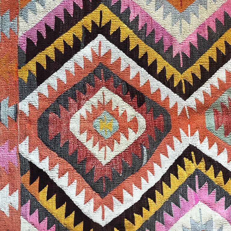 Colorful geometric Kilim rug from Turkey. Great for by a bed, in a nursery, front door or foyer. Colors in pink, yellow, black, orange, red white.