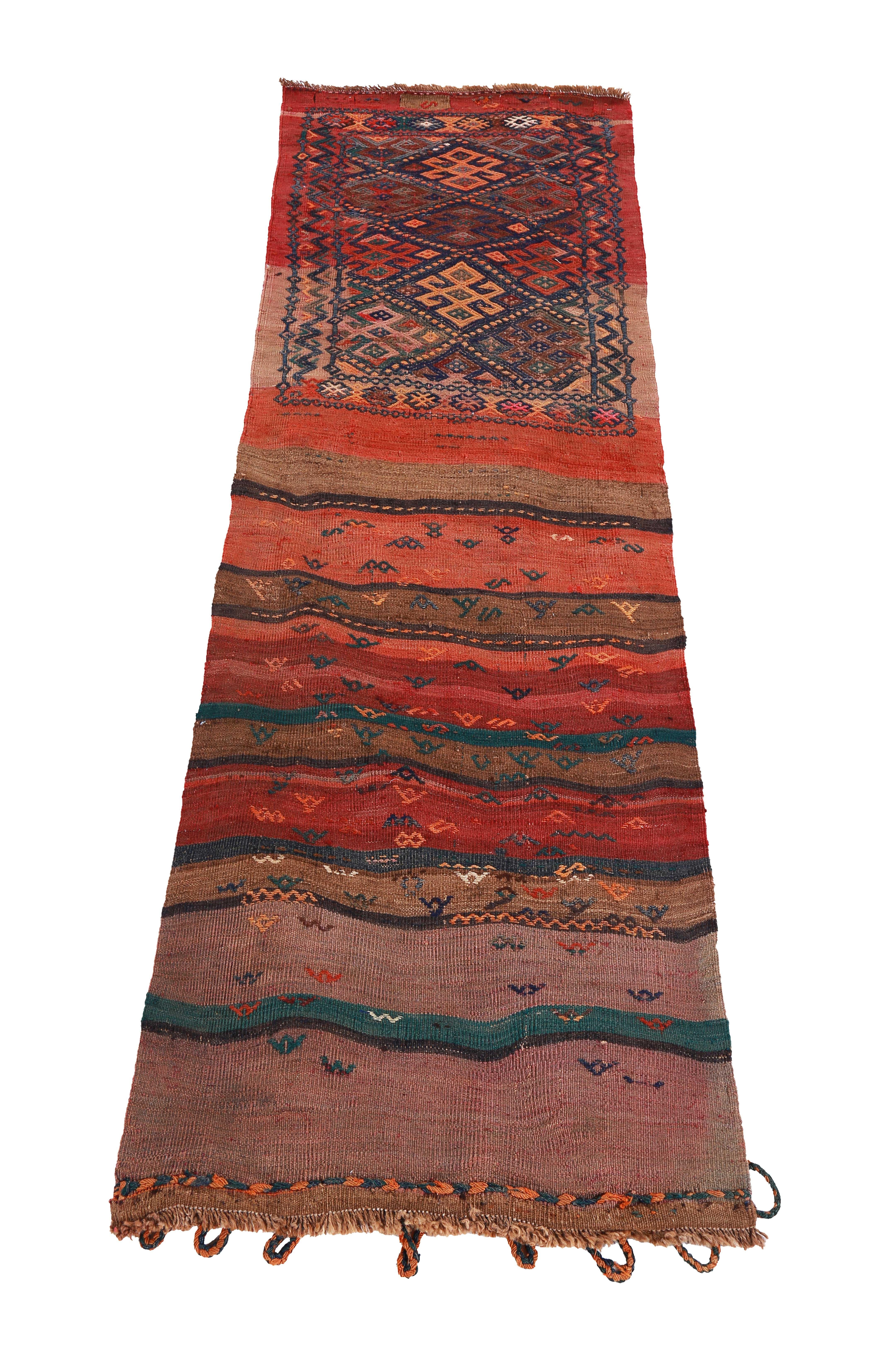 Turkish rug handwoven from the finest sheep’s wool and colored with all-natural vegetable dyes that are safe for humans and pets. It’s a traditional Kilim flat-weave design featuring a red and orange field with tribal stripes in green and brown.