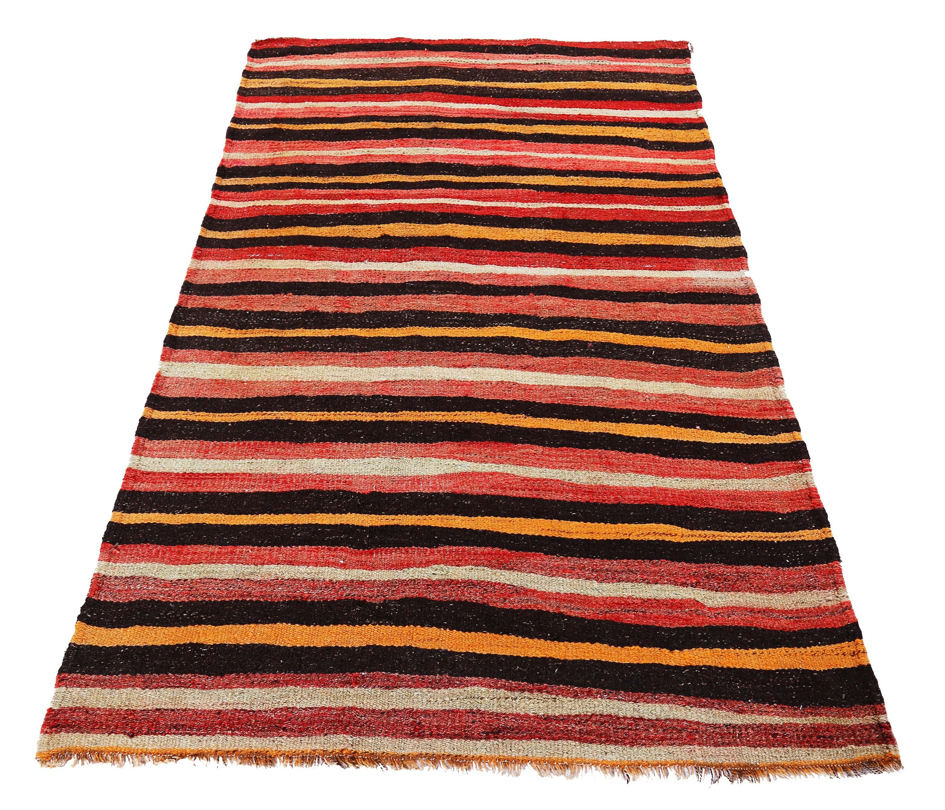 Turkish runner rug handwoven from the finest sheep’s wool and colored with all-natural vegetable dyes that are safe for humans and pets. It’s a traditional Kilim flat-weave design featuring a black and orange stripes over a red and ivory field. It’s