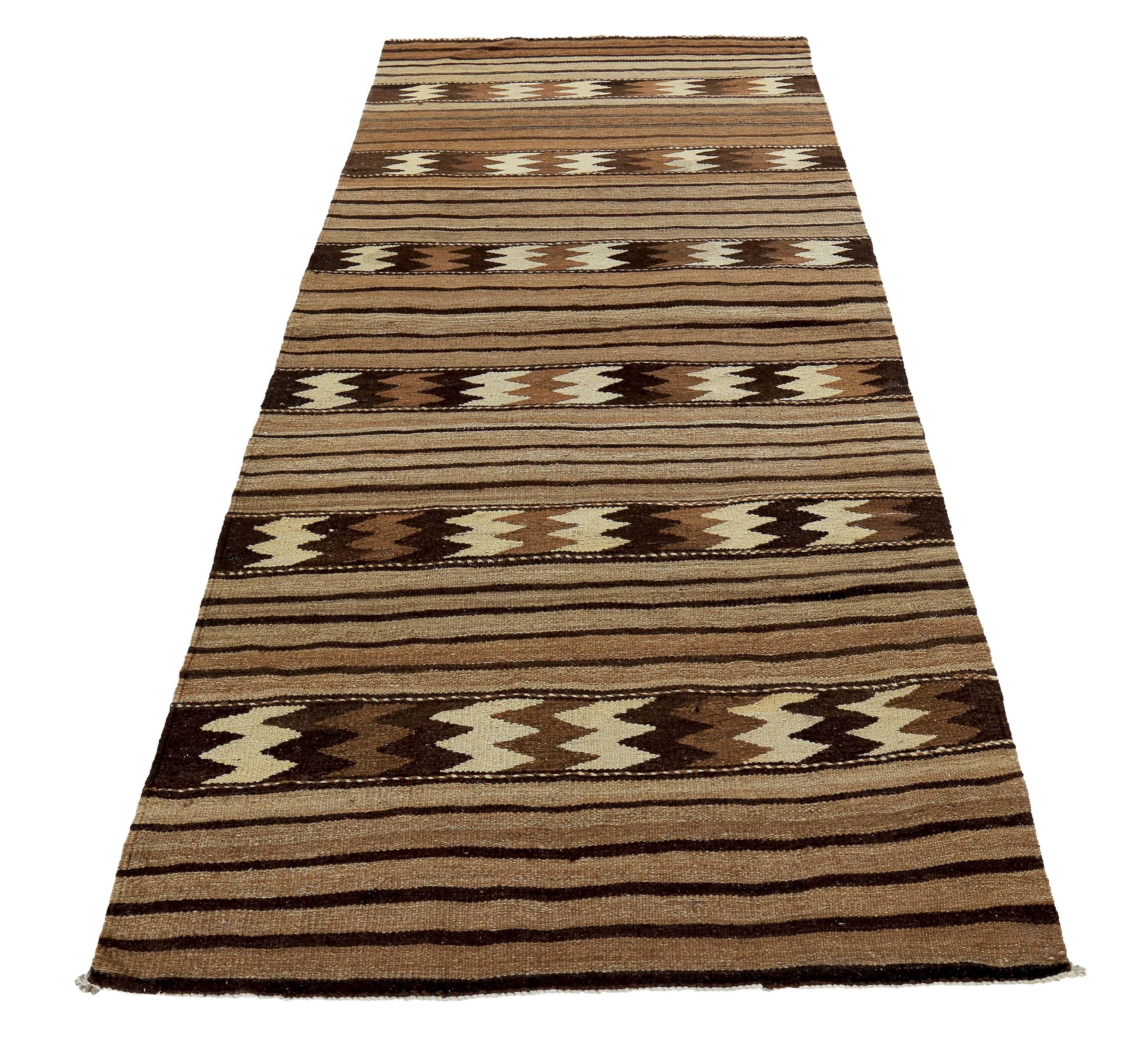 Turkish rug handwoven from the finest sheep’s wool and colored with all-natural vegetable dyes that are safe for humans and pets. It’s a traditional Kilim flat-weave design featuring tribal stripes in brown and ivory over a beige field. It’s a